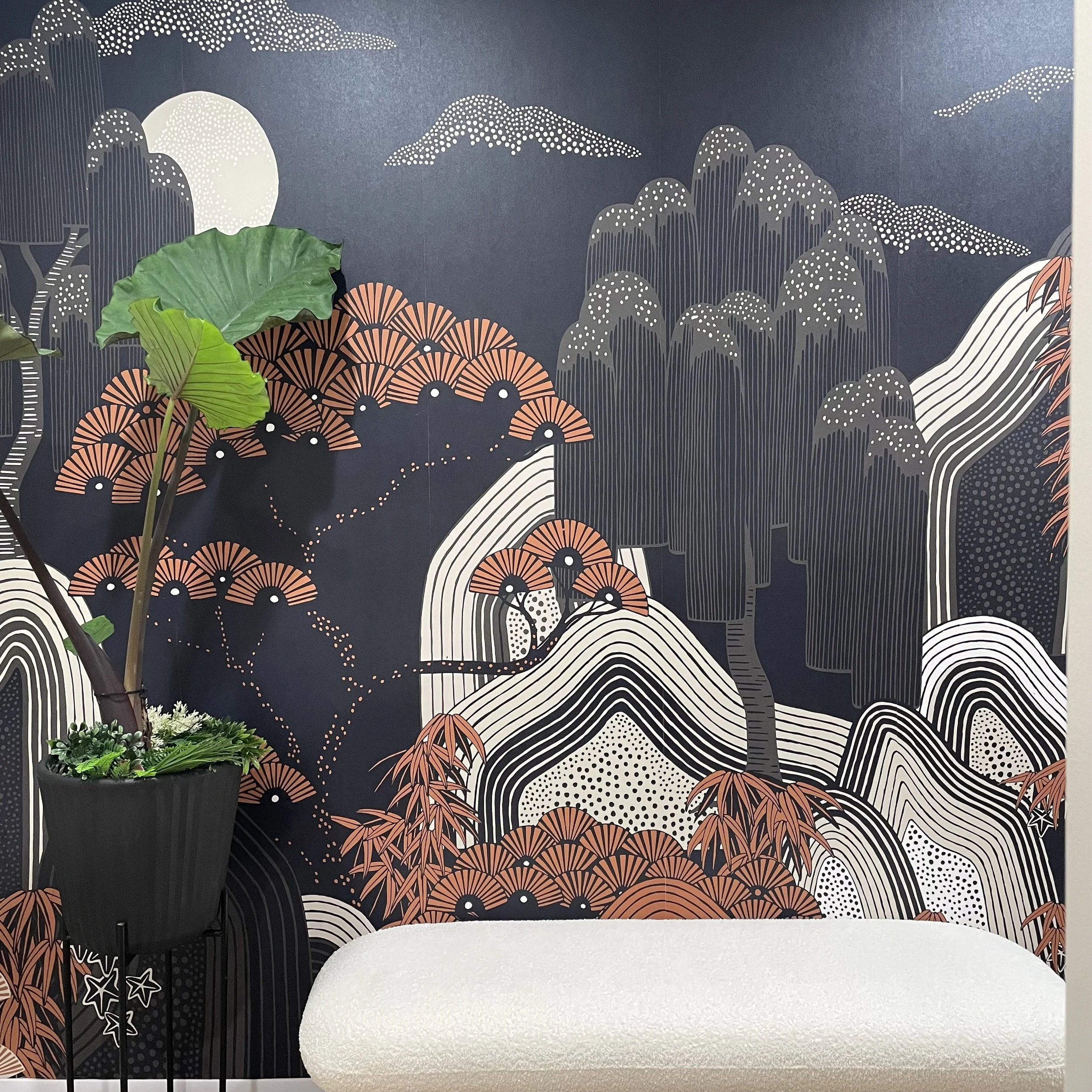 Decorative wall mural featuring stylized mountain and tree landscape in black, white, and peach tones, with a moon and clouds in the background.