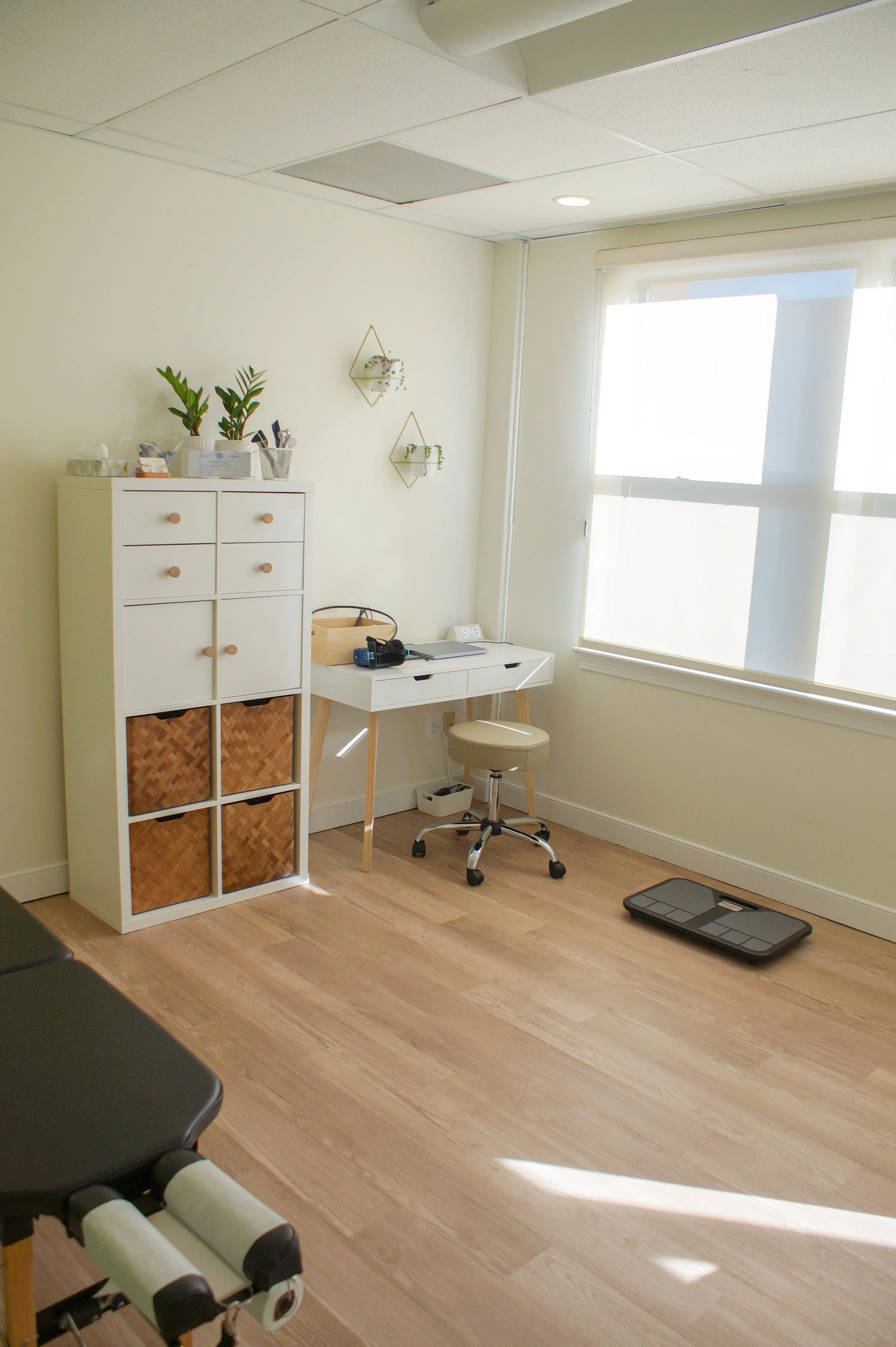 clinic examination room with cabinet, examination table, and desk.