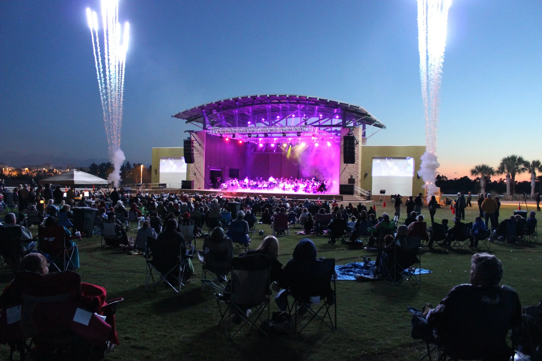 Visitors sitting in folding chairs watching a concert at Aaron Bessant Park near Pier Park in Panama City Beach