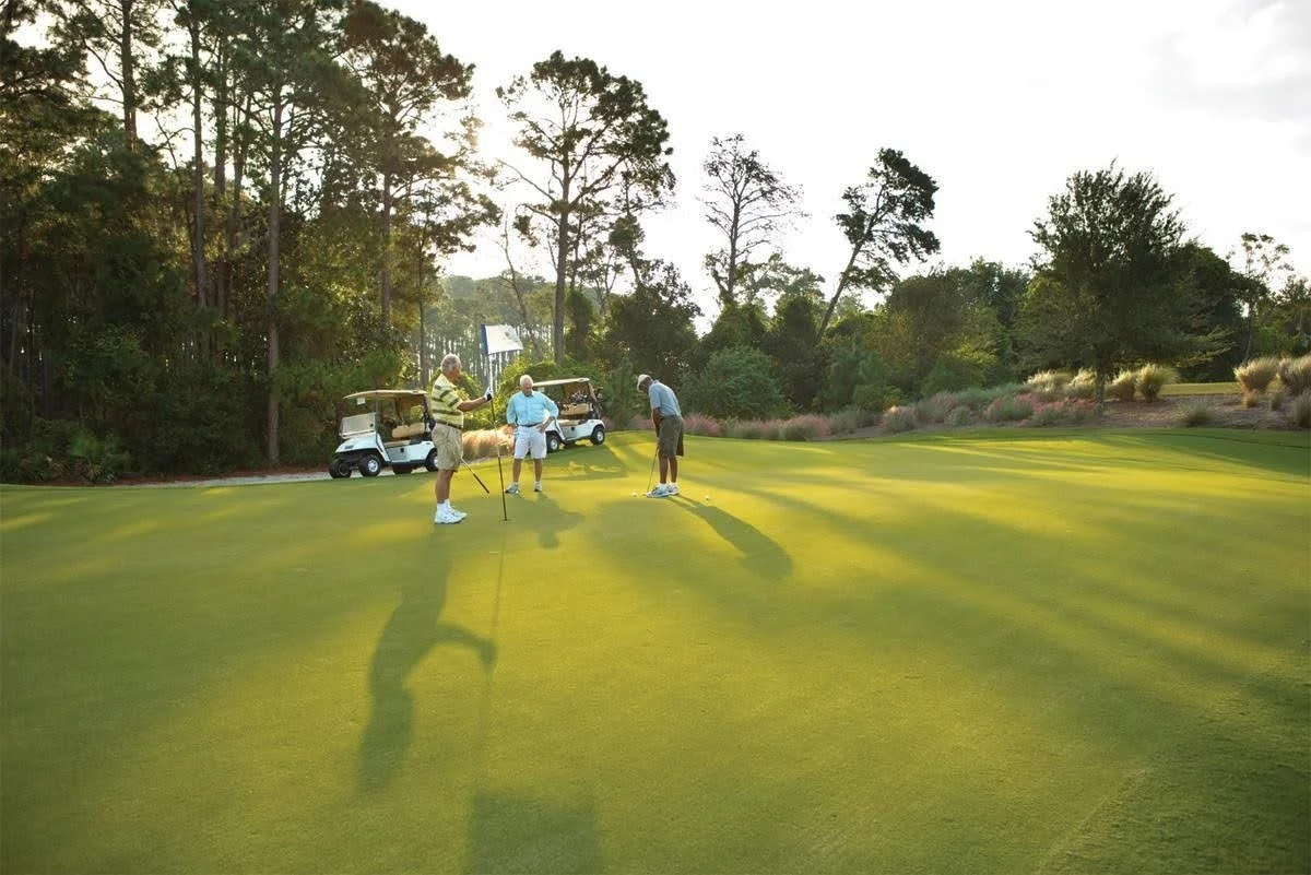 Golfers gathered around the hole on a golf course putting green in Panama City Beach, Florida