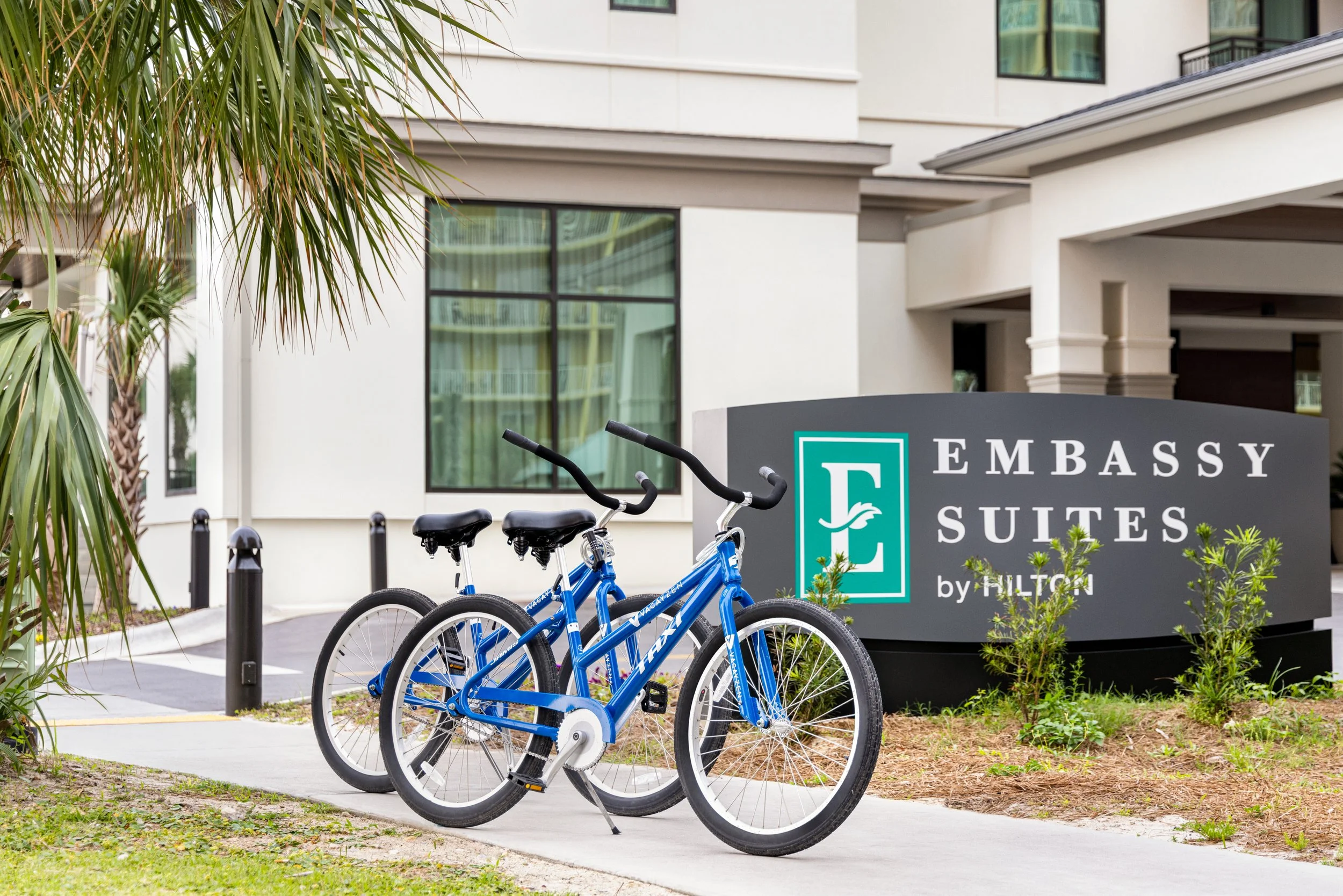 Two blue bicycles parked in front of the Embassy Suites by Hilton sign in Panama City Beach, Florida