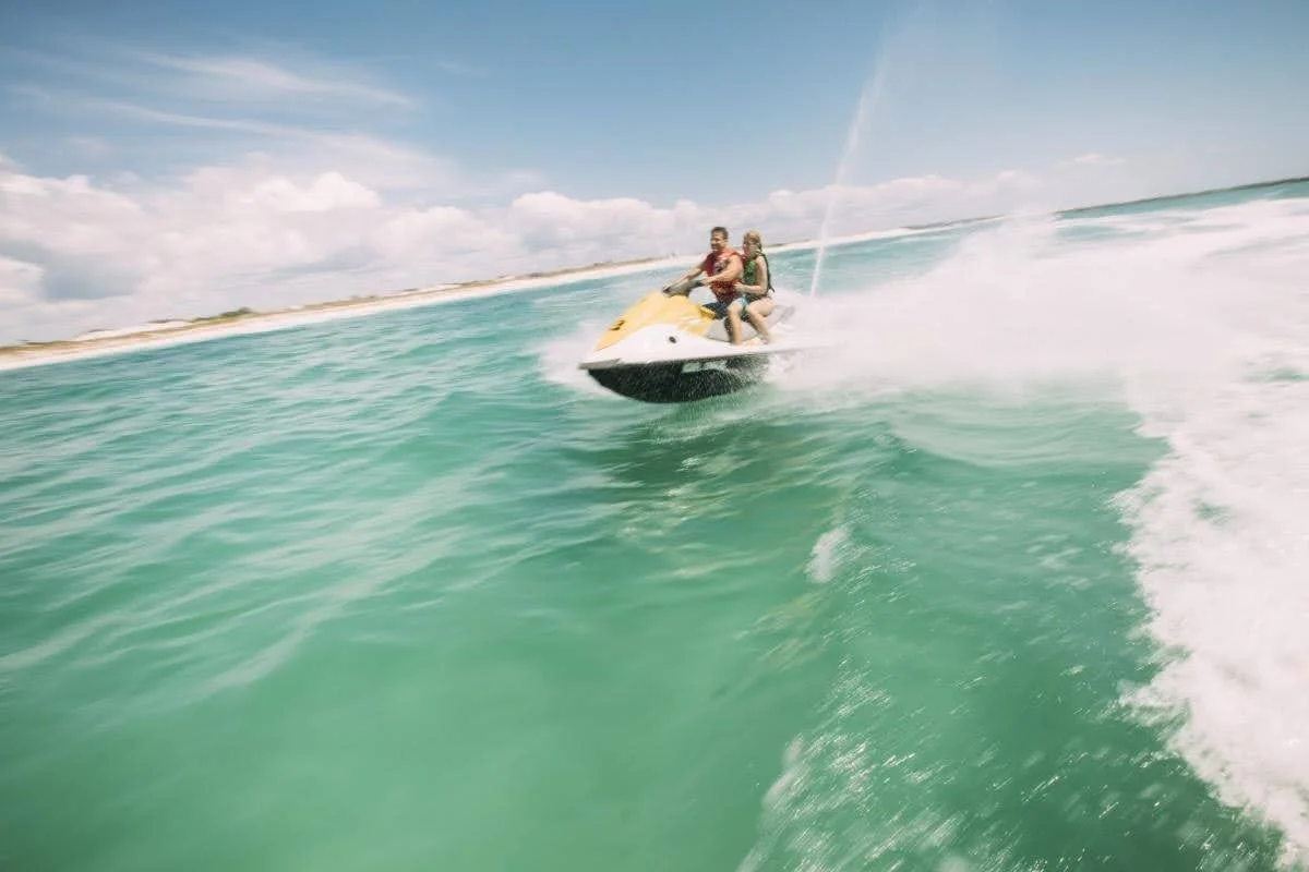 Two people riding a jet ski in the Gulf waters of Panama City Beach, Florida.