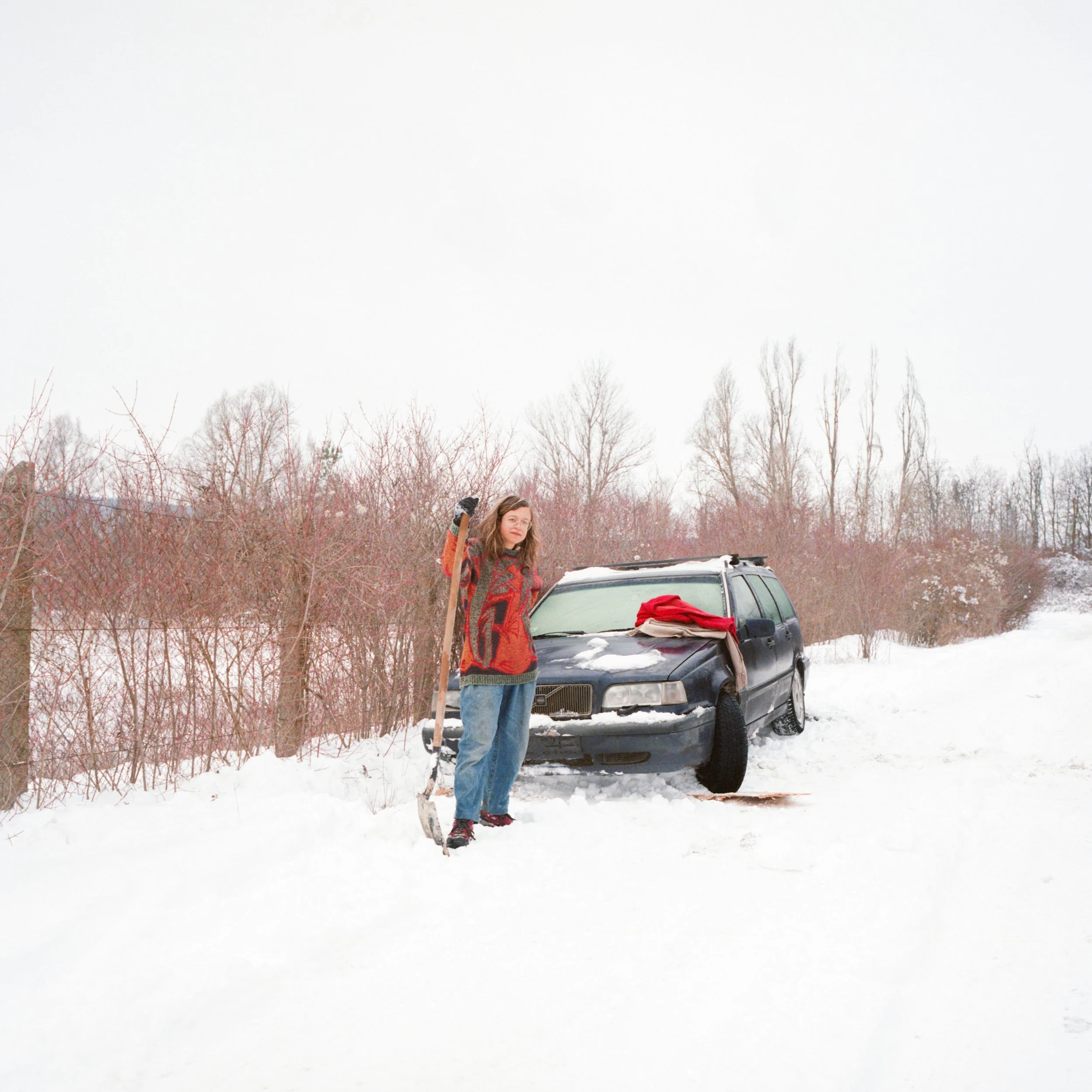 Person beside car in snowy rural landscape