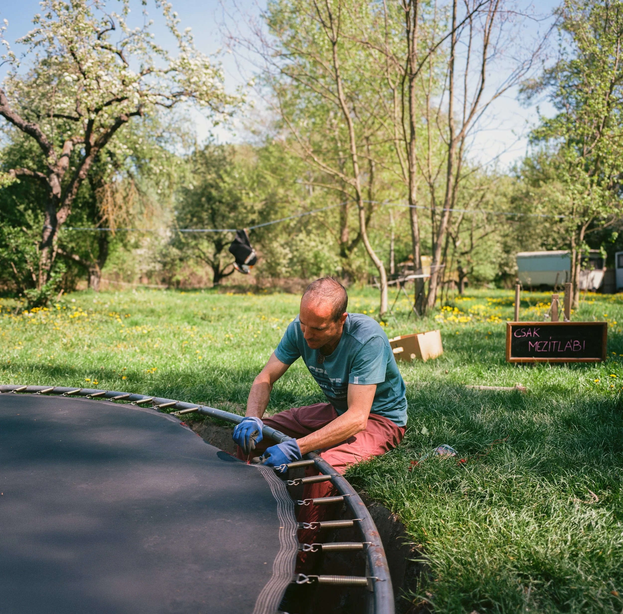 Man repairing trampoline in rural garden