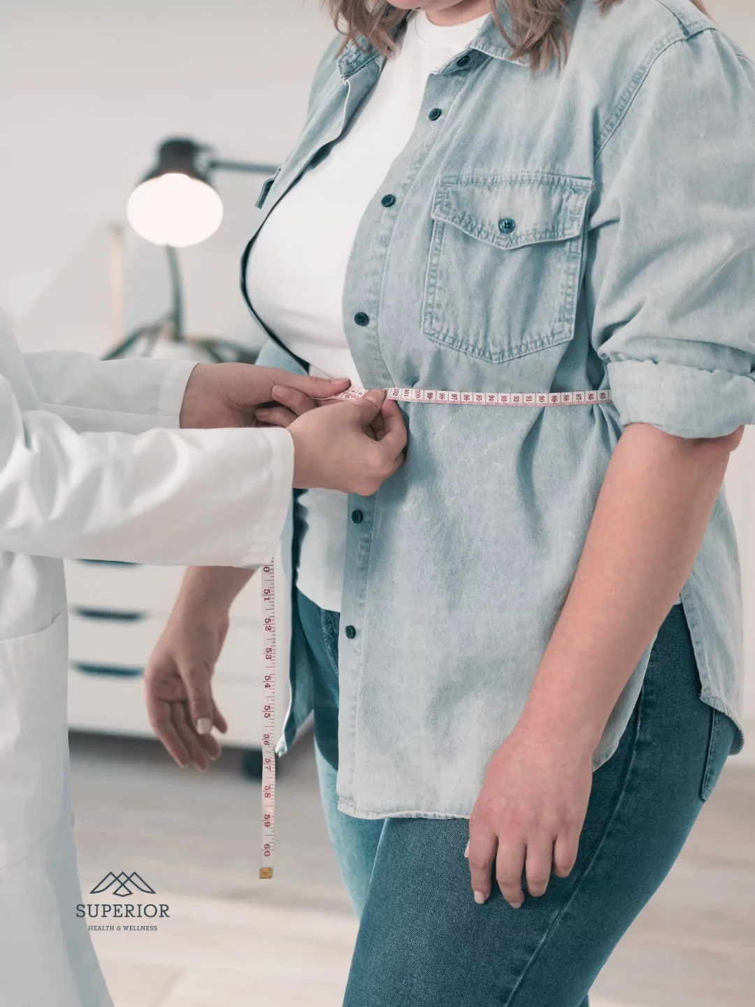Medical professional measuring a woman's waist with a tape measure, in a health and wellness setting.