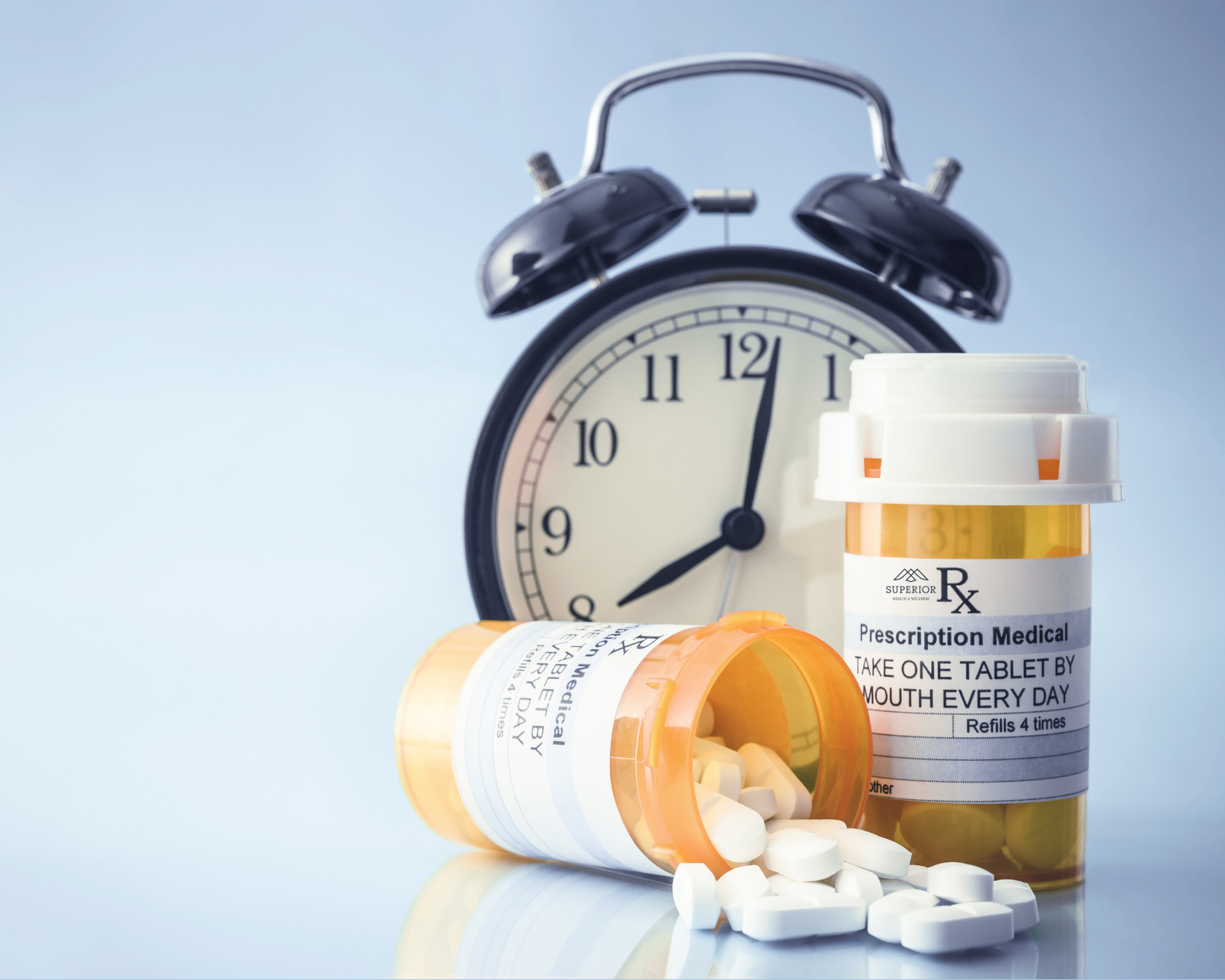 black analog clock with two prescription medication bottles white pill tablets