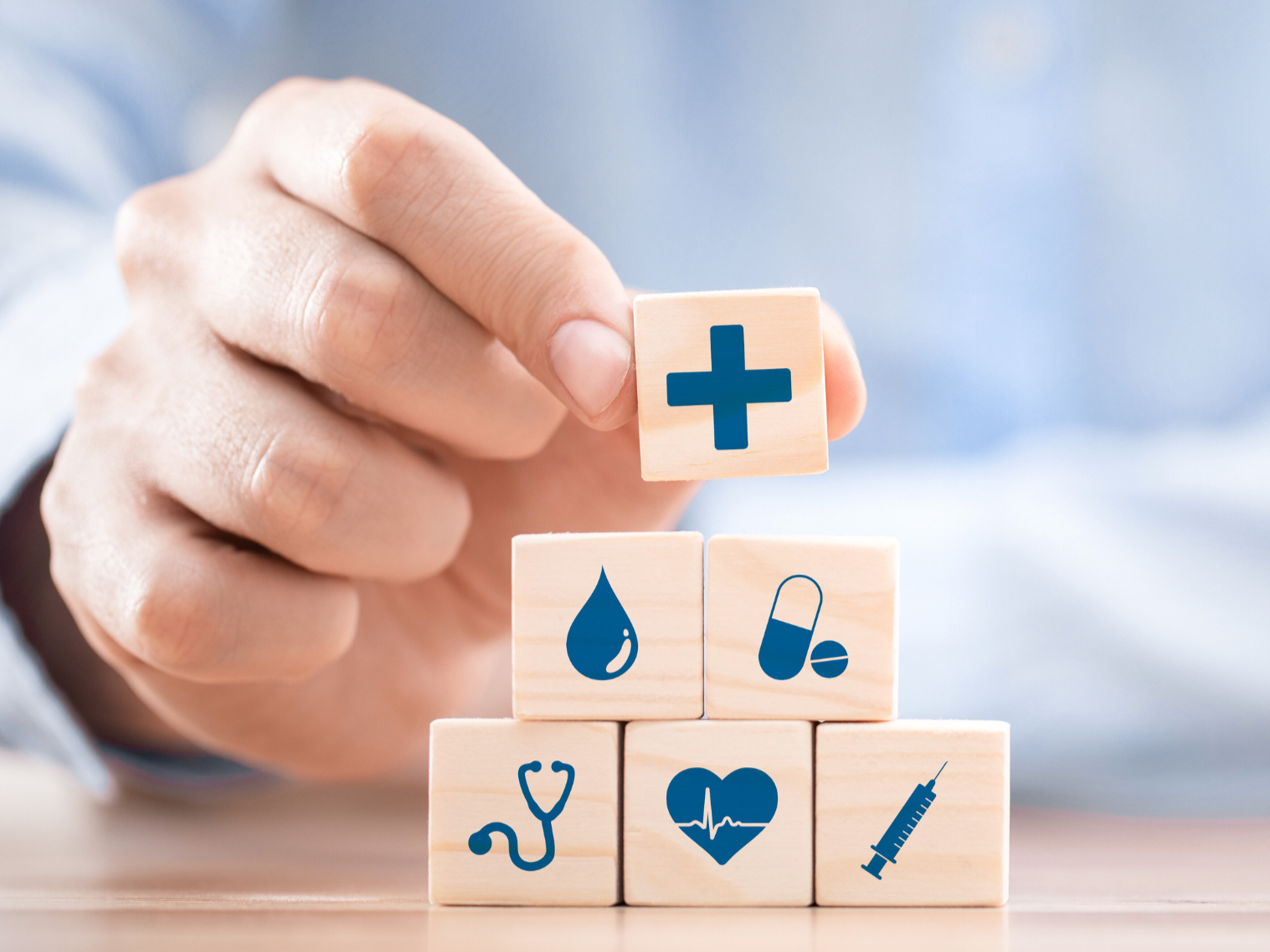 male stacking wooden blocks with blue medical icons