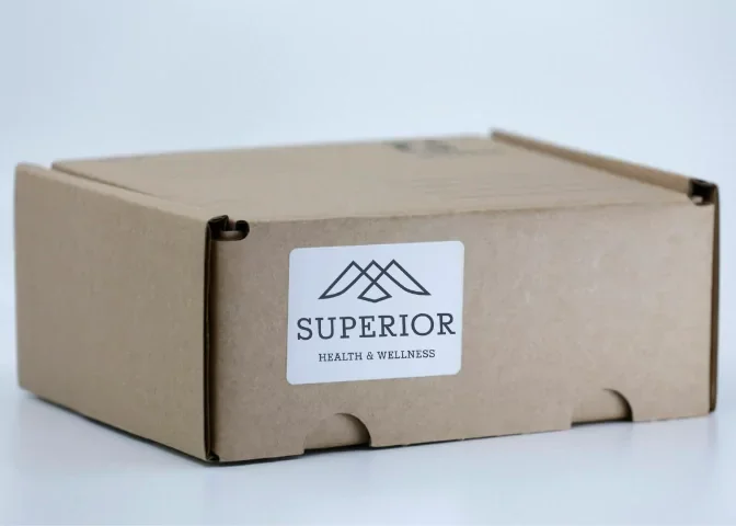 Brown cardboard box with a white label that reads "Superior Health & Wellness" and has a mountain-like logo.