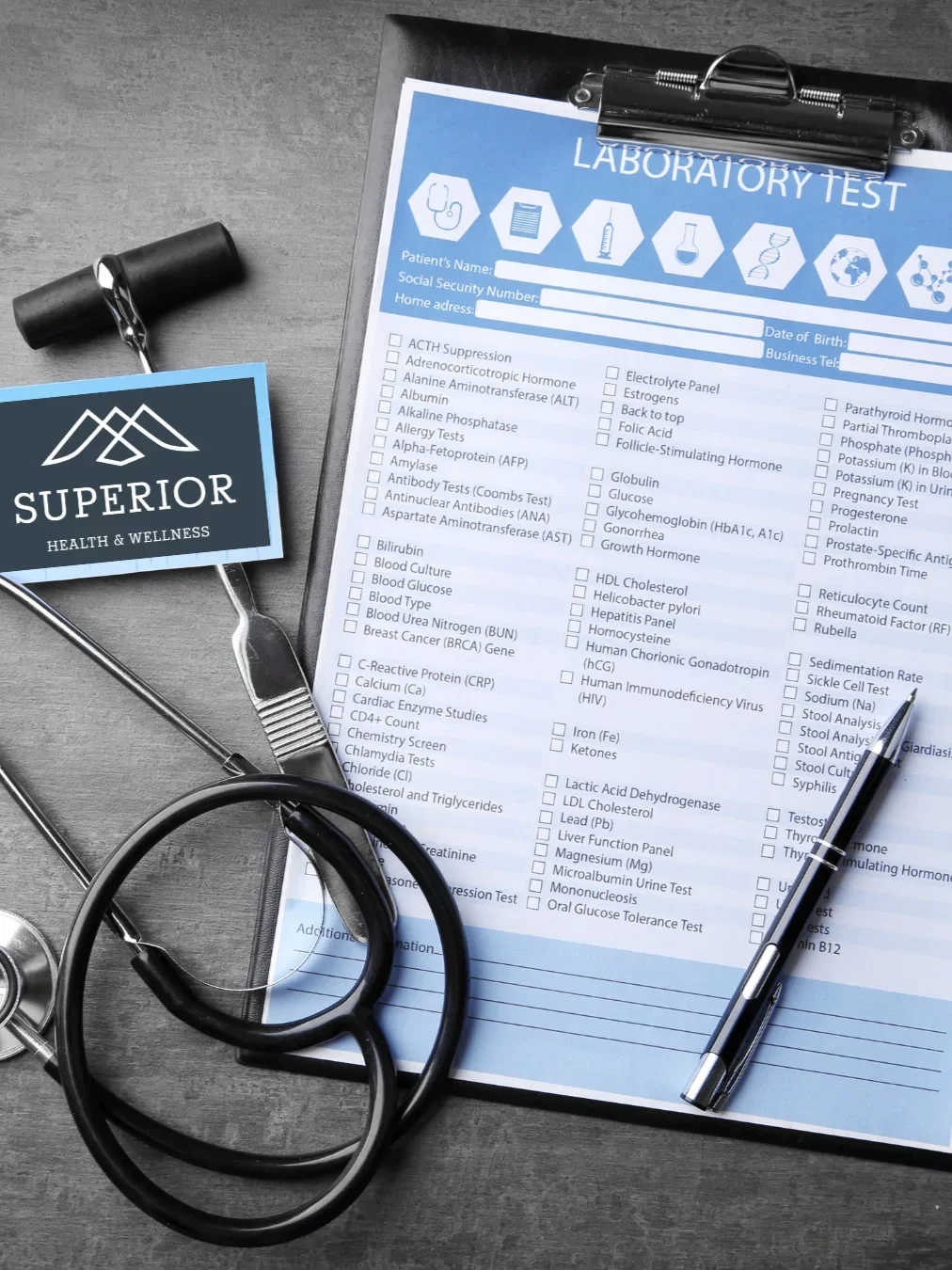 A laboratory test request form on a clipboard surrounded by medical equipment including a stethoscope, a pen, and a badge labeled "Superior Health & Wellness."
