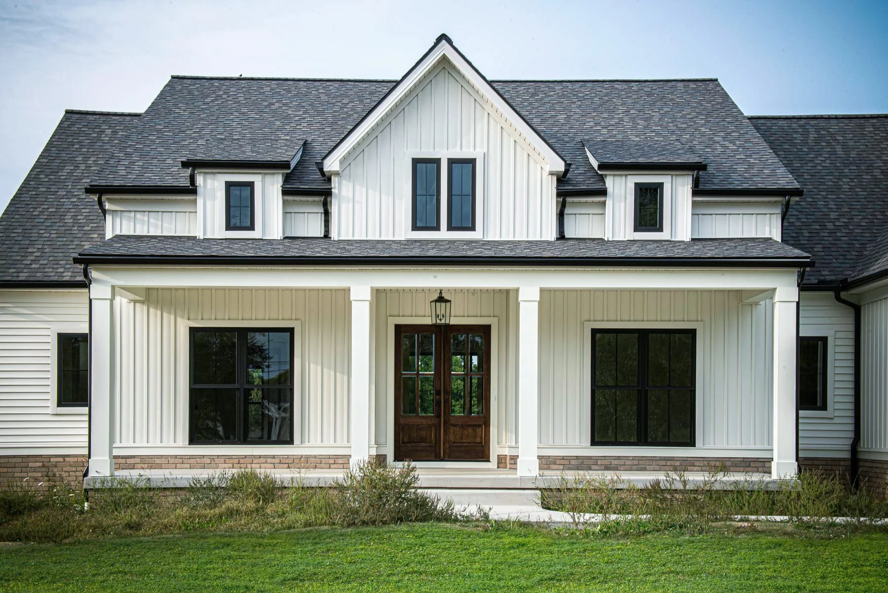 Modern farmhouse custom home with white board-and-batten siding, black windows, and a covered front porch.