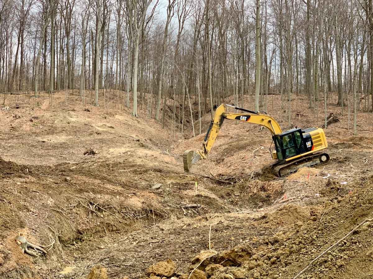 Excavator clearing and grading a wooded building lot in Northeast Ohio