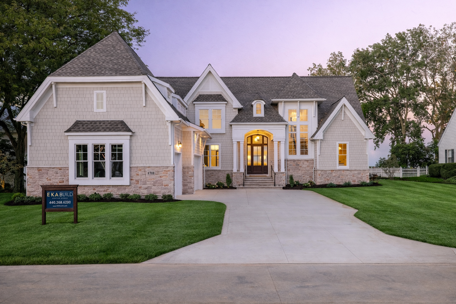 Custom home built by EKA Build featuring shingle siding, stone foundation, and arched entryway