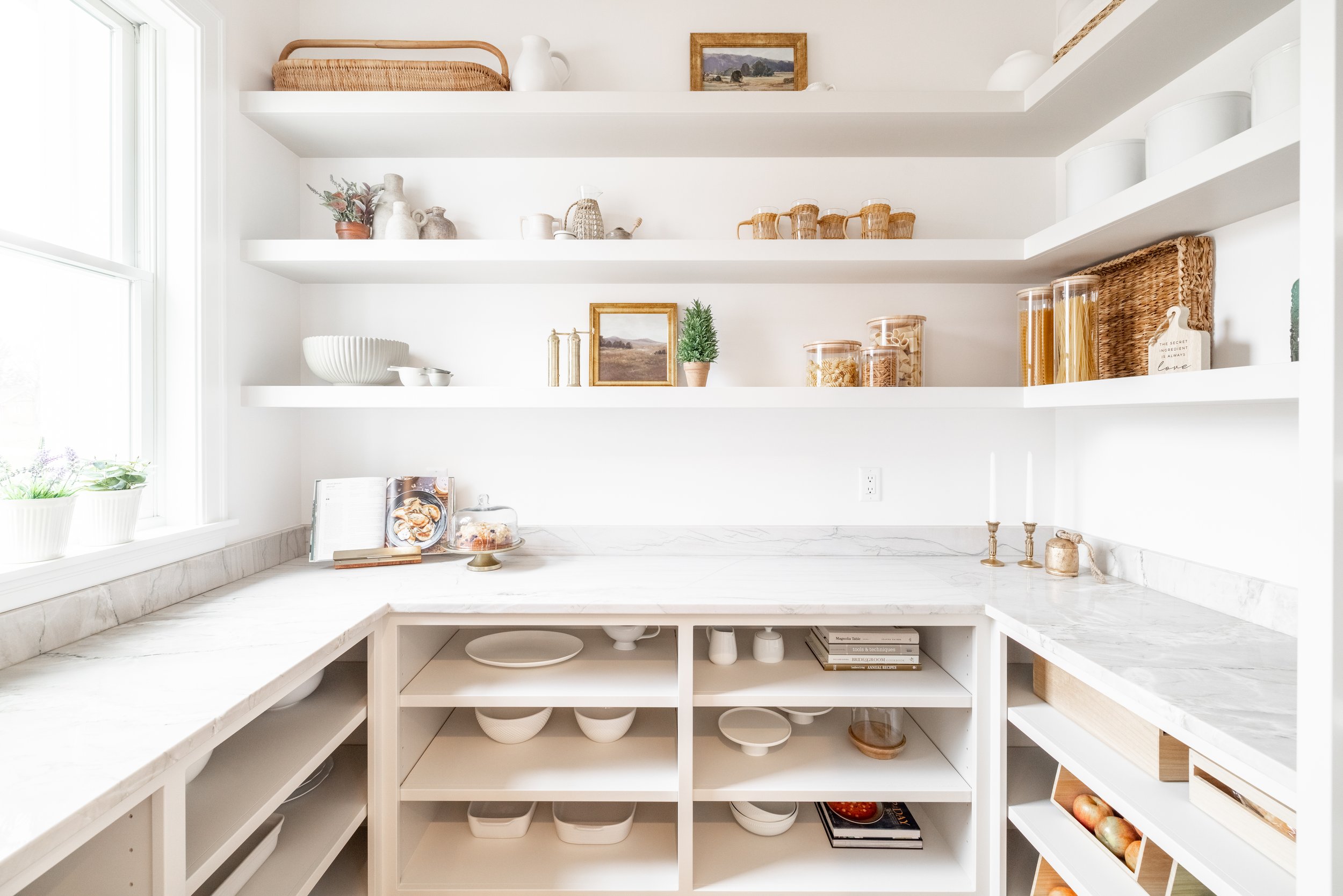 Custom pantry with white cabinetry, open shelving, and marble countertops styled with dishes and pantry storage.