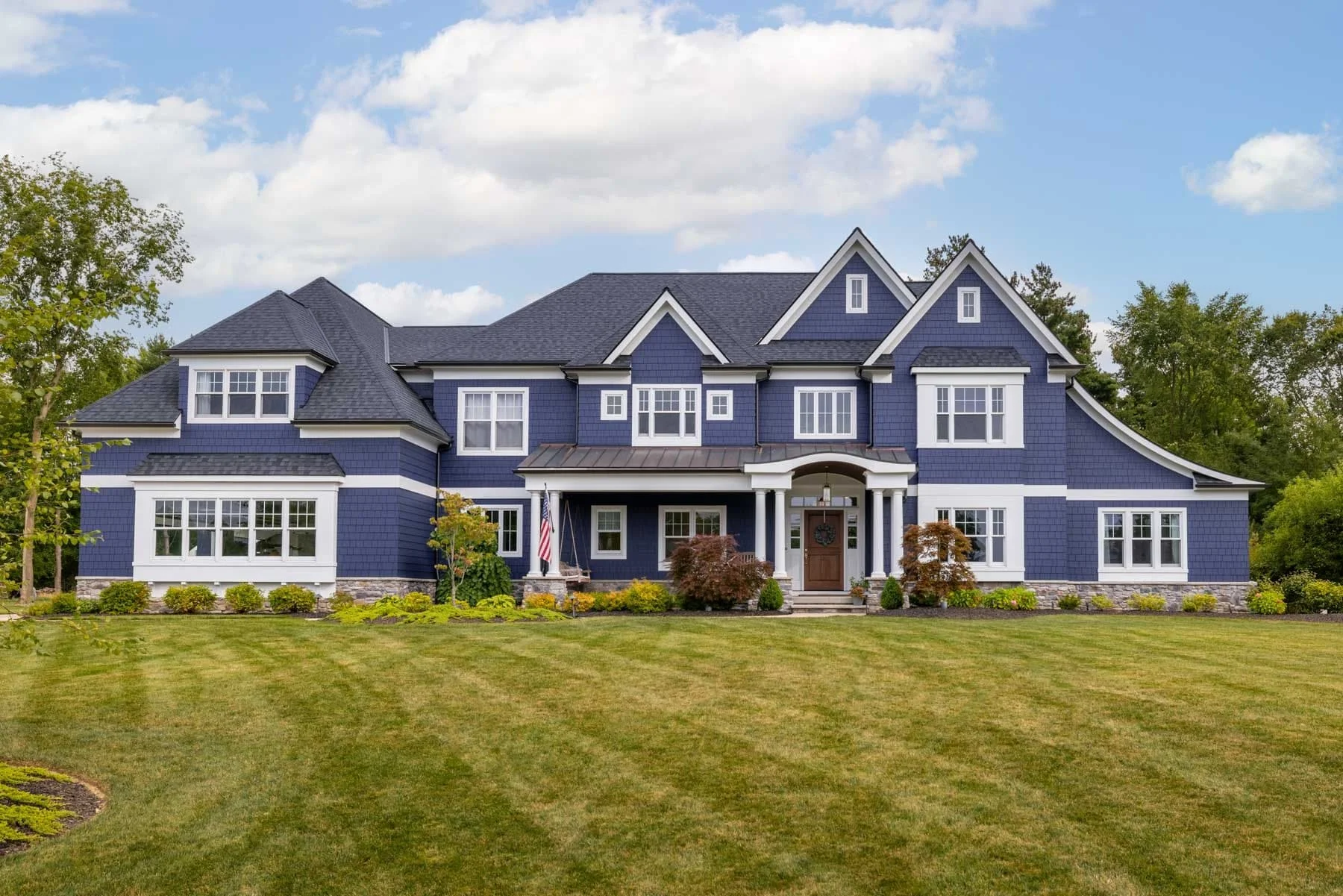 Navy blue custom home in Hinckley, Ohio, with detailed rooflines, white trim, large windows, and landscaped front yard