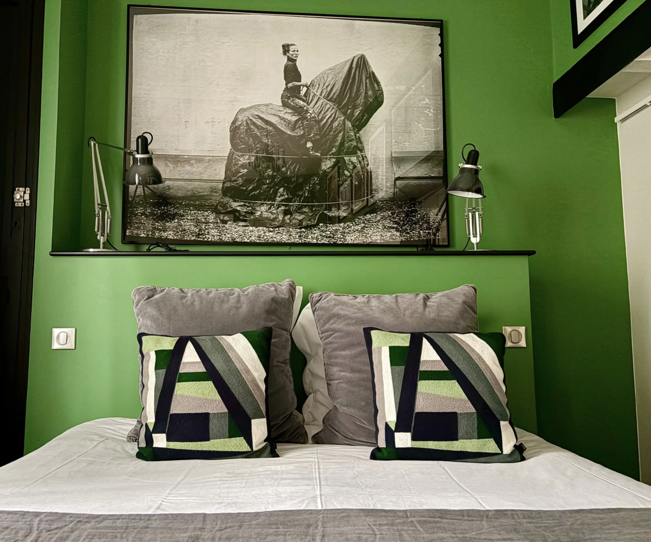 Photo en noir et blanc d'une femme chevauchant une sculpture en forme d'éléphant recouverte d'une couverture en tissu, dans un espace intérieur avec un mur vert.