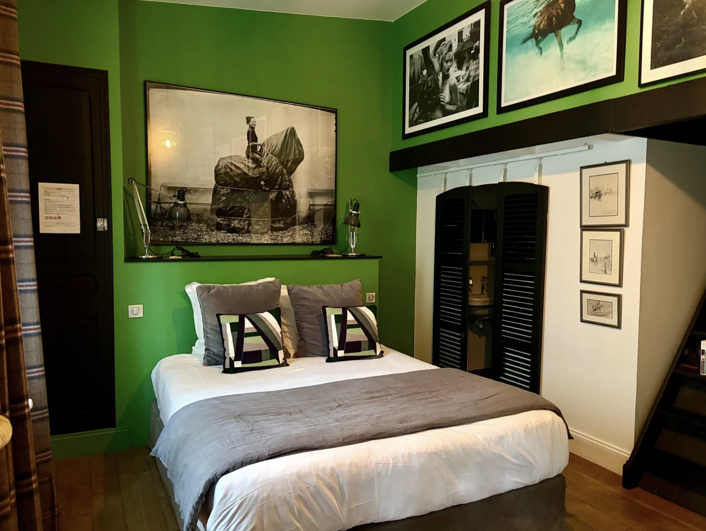 Chambre avec mur vert, lit avec oreillers gris et décorations murales