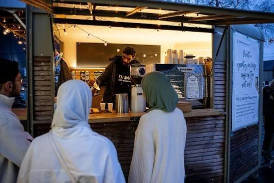 People ordering from a food stand at an outdoor event during evening.
