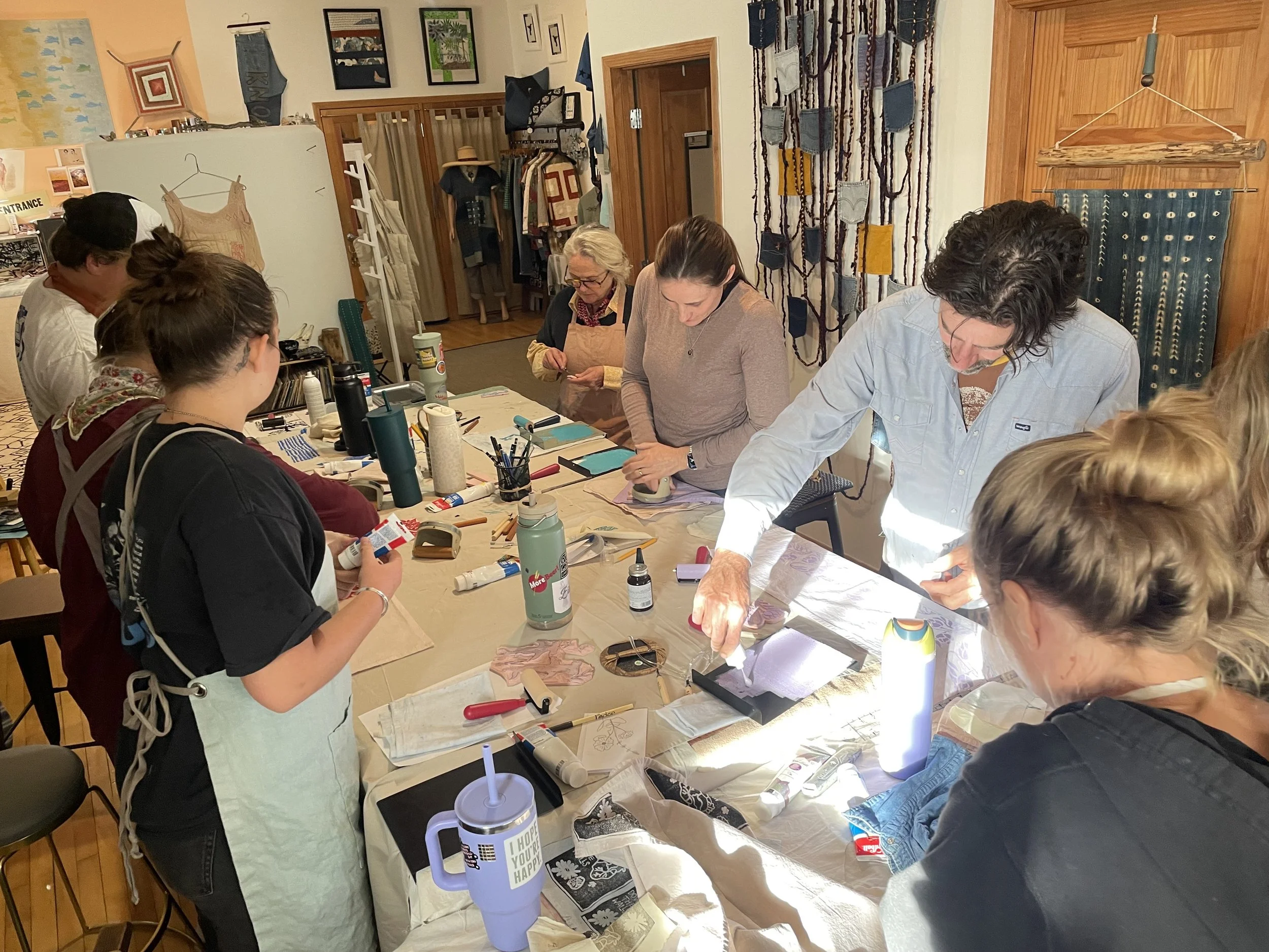 Students learning the art of block printing around a table.