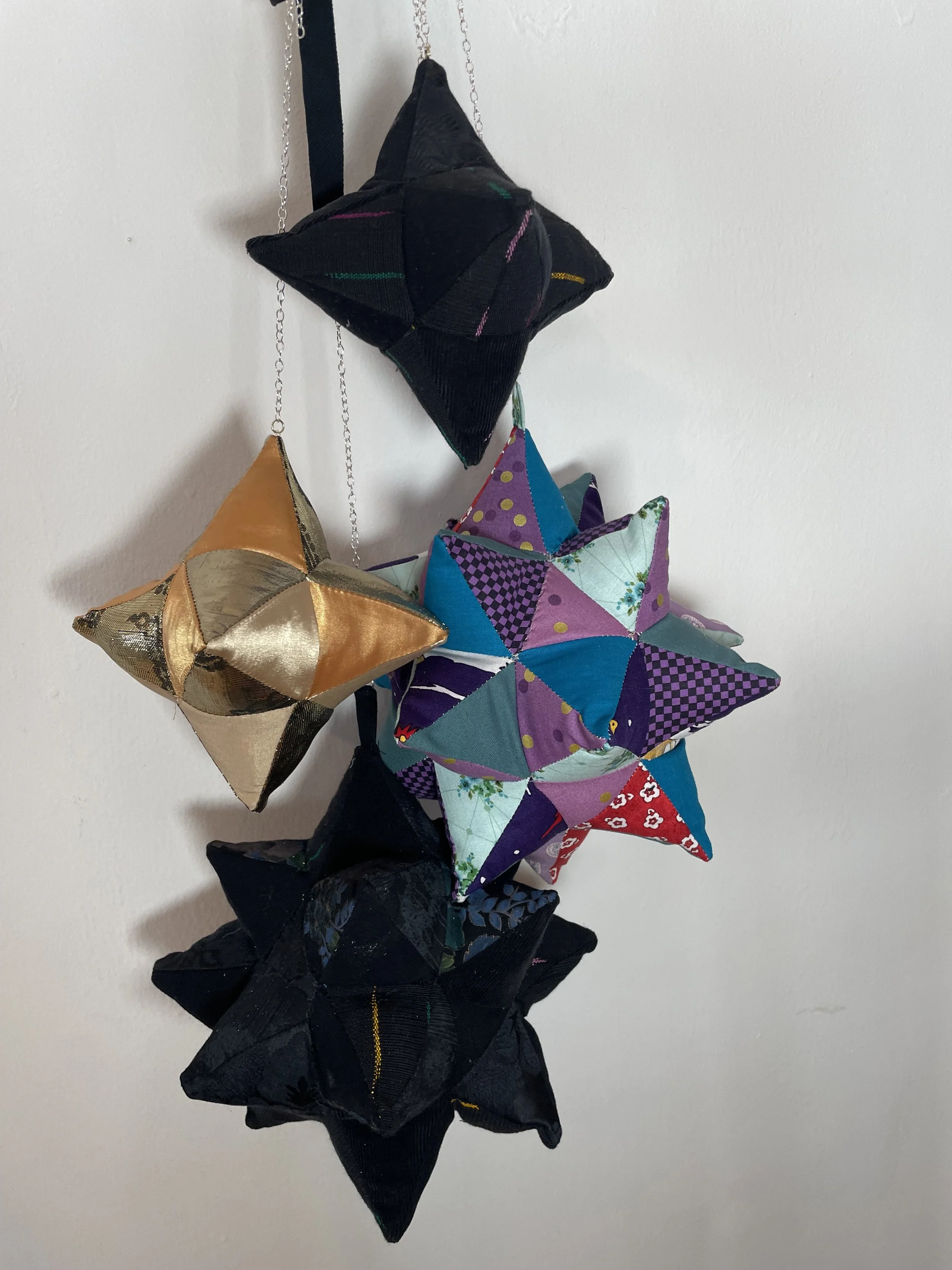 Colorful soft sculptures in the shape of stars hanging on a wall.