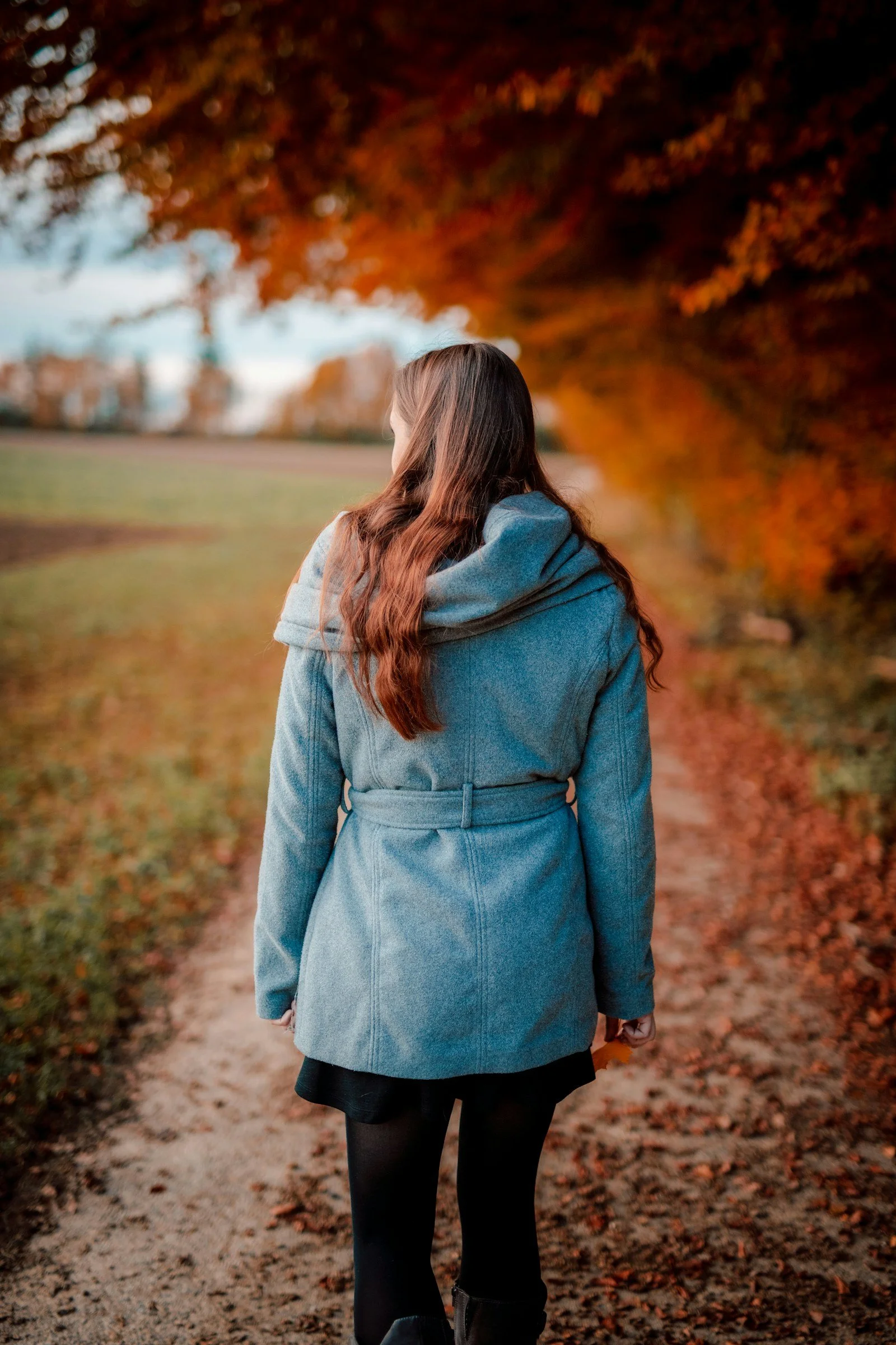 Woman walking alone on a leafy autumn path