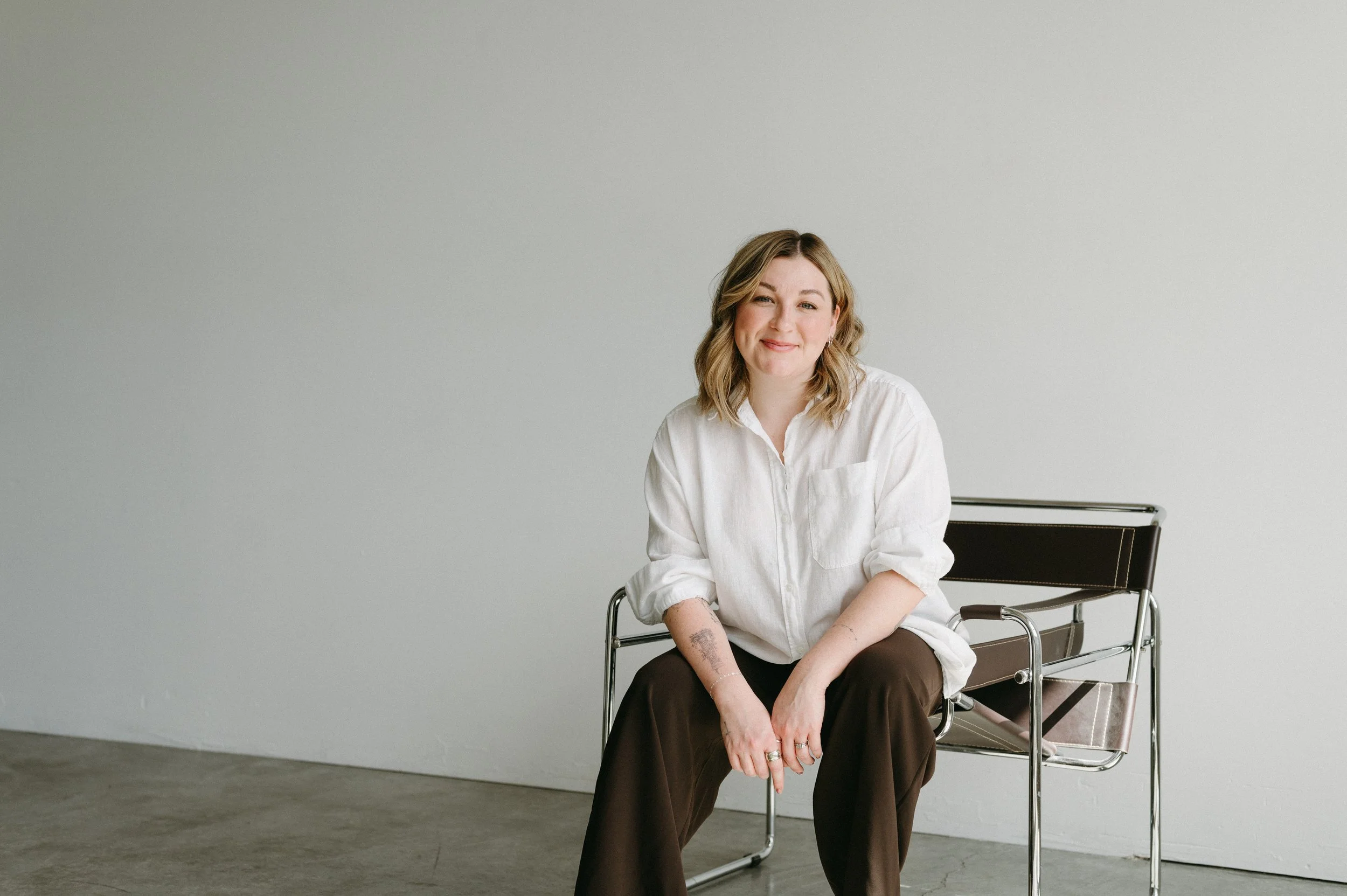 Dr. Shelby Kittinger, orange county psychologist in her Newport Beach office, sitting against a white wall in a cream button-up.