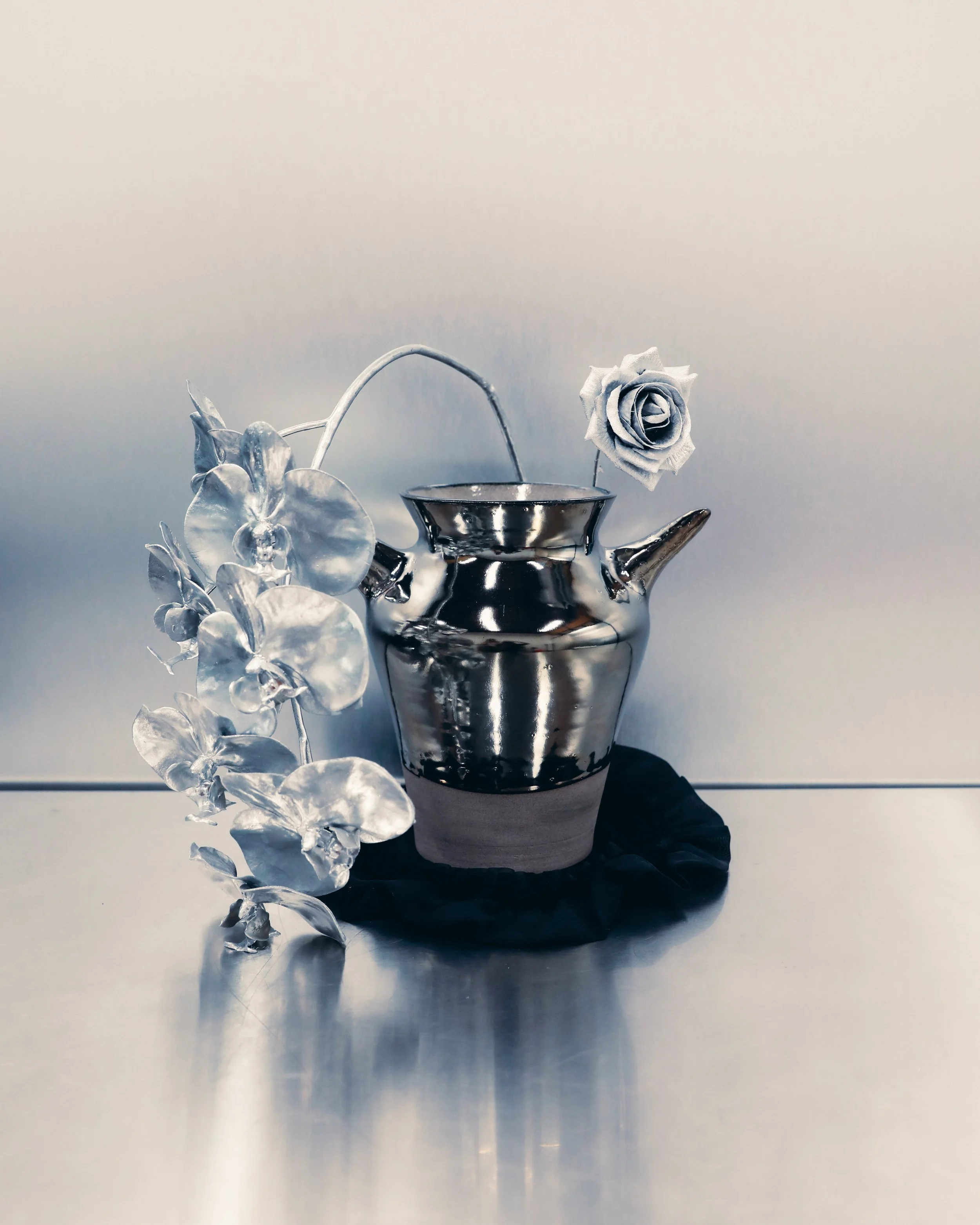 Metallic vase with silver orchid.