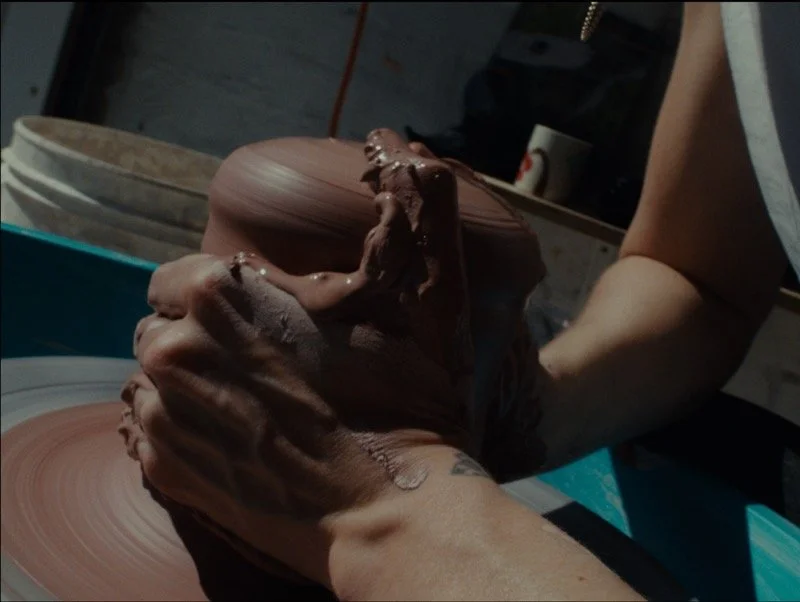 Person shaping clay on a pottery wheel in a pottery studio.