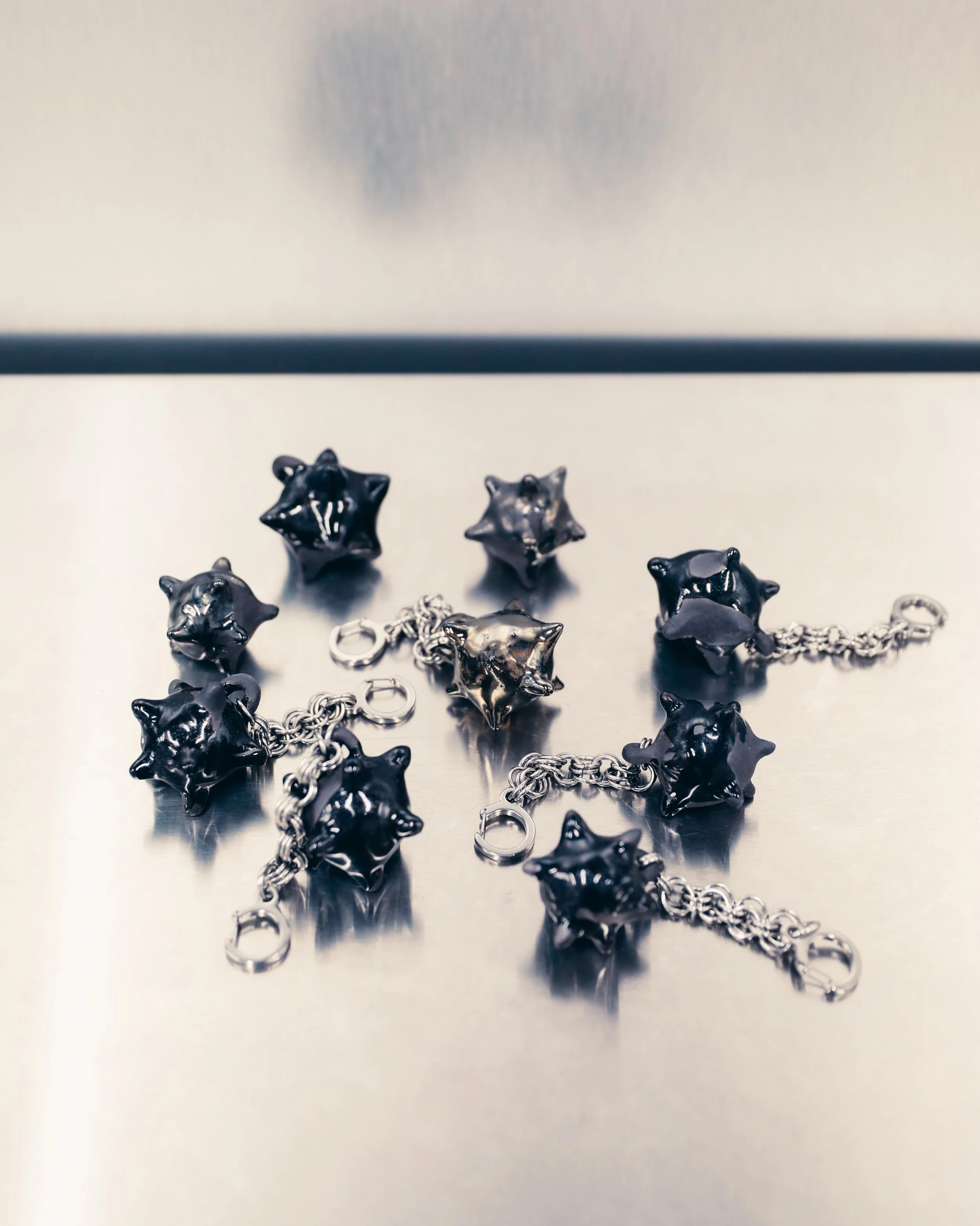 Collection of black star-shaped charms with silver chains on a reflective surface.