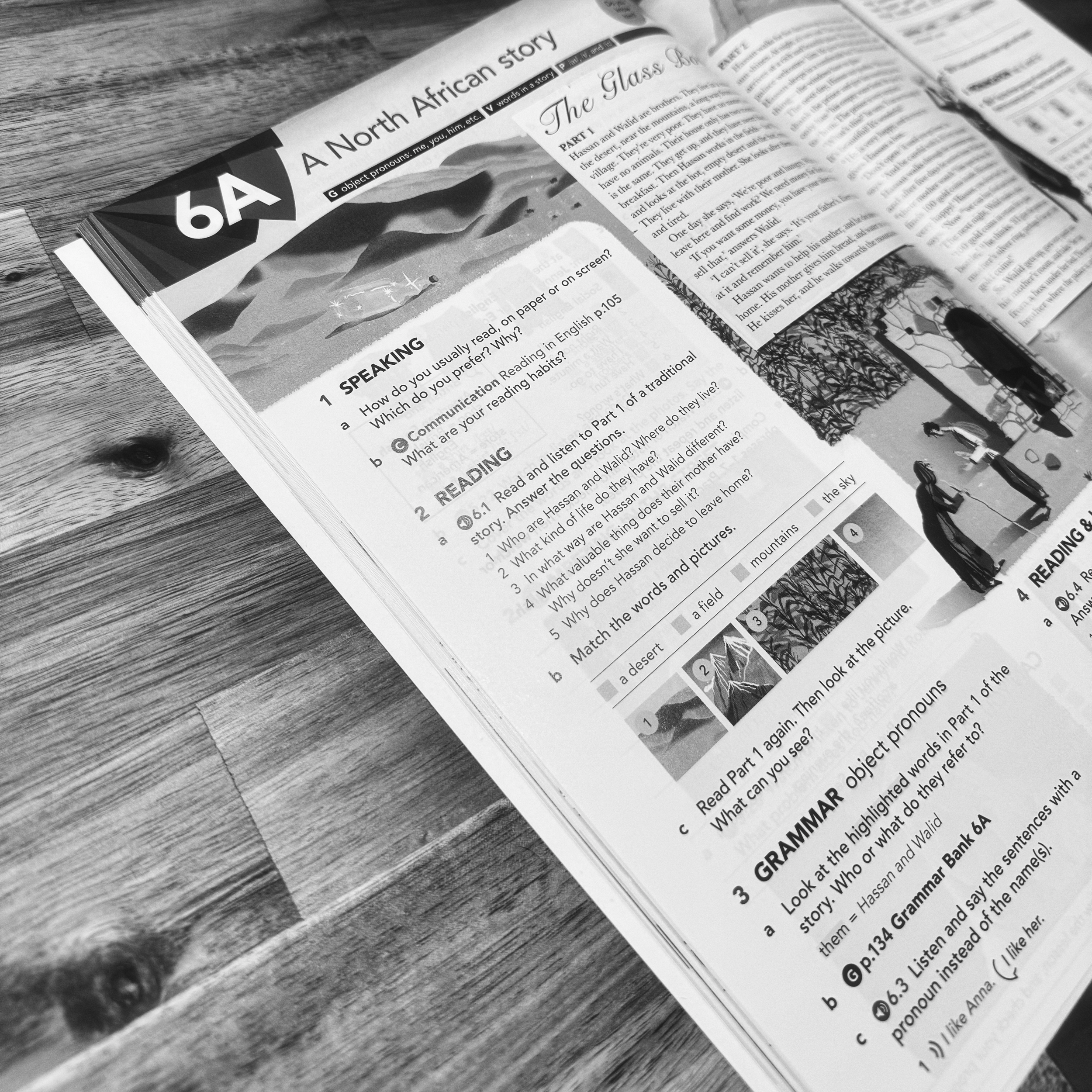 A black and white photograph of an English language textbook on a wooden table