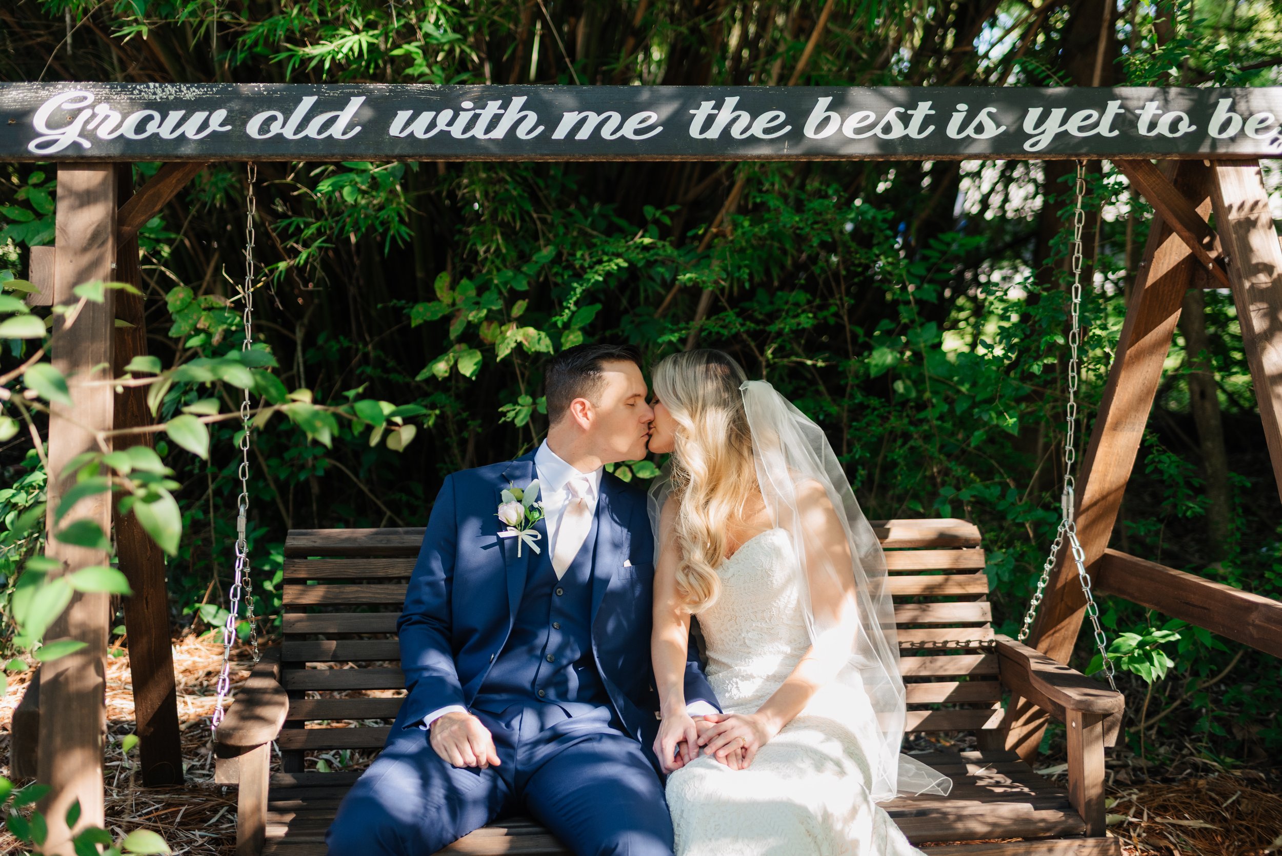 Bride and groom kissing on a swing bench in the garden at 108 W Main, Moncks Corner, SC.