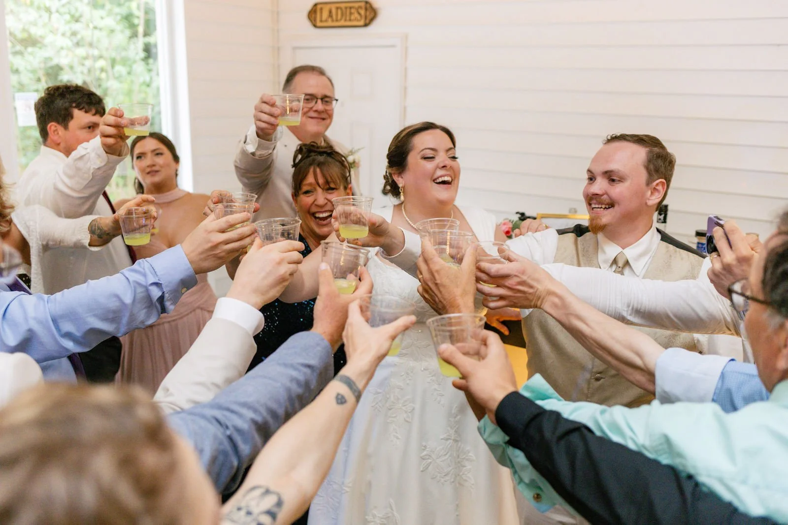 A newlywed couple shares a celebratory toast with wedding guests.