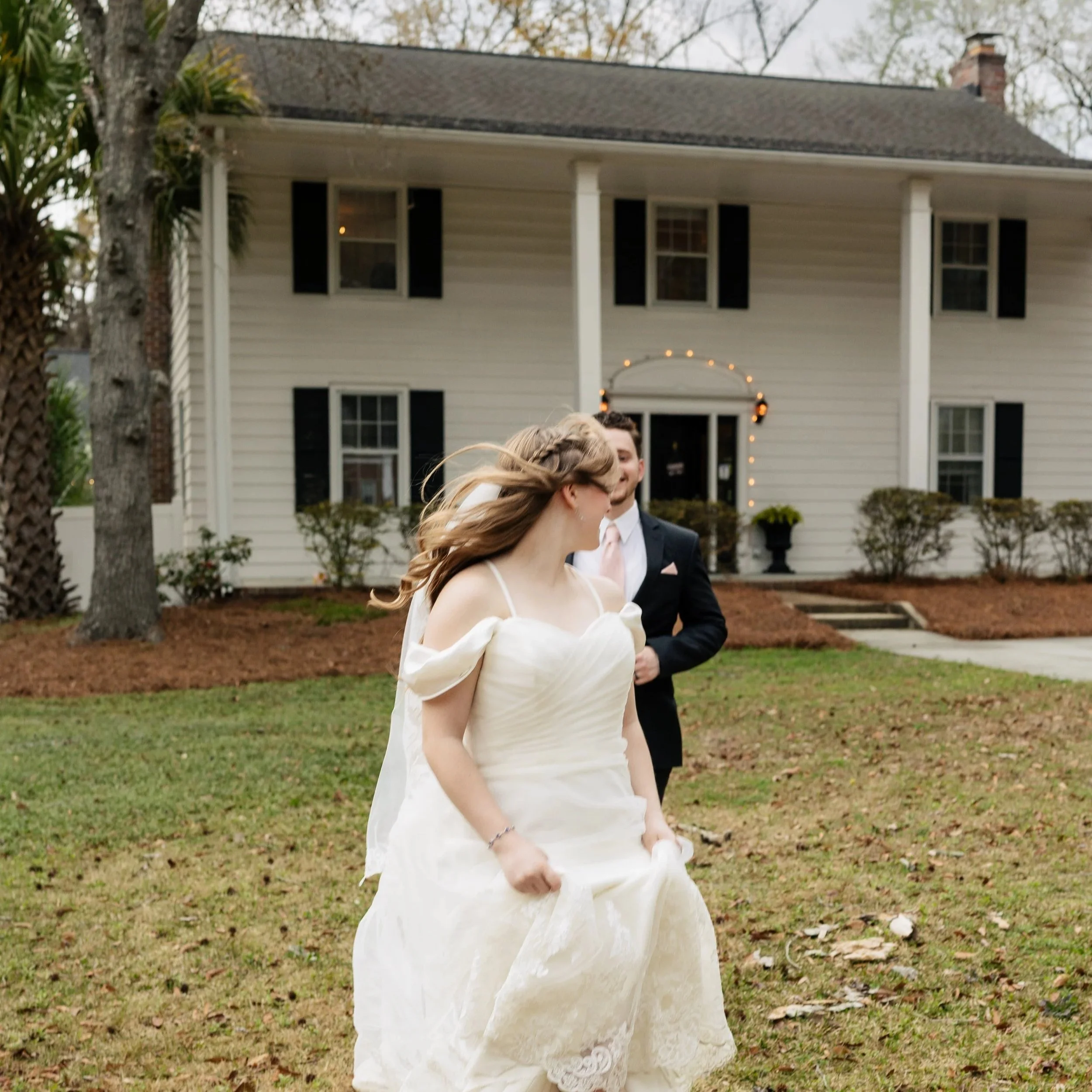 Bride and groom walking outside at 108 W Main in Moncks Corner, SC in front of the historic white home wedding venue.