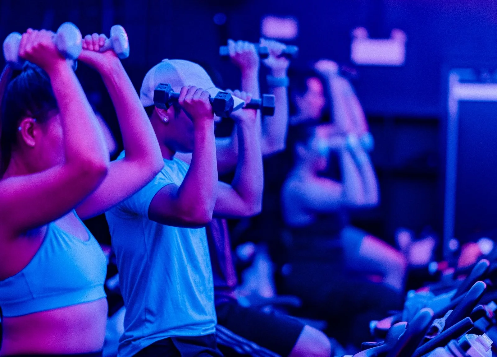 People holding weights at their shoulders during a spin class at YYC Cycle in Calgary.