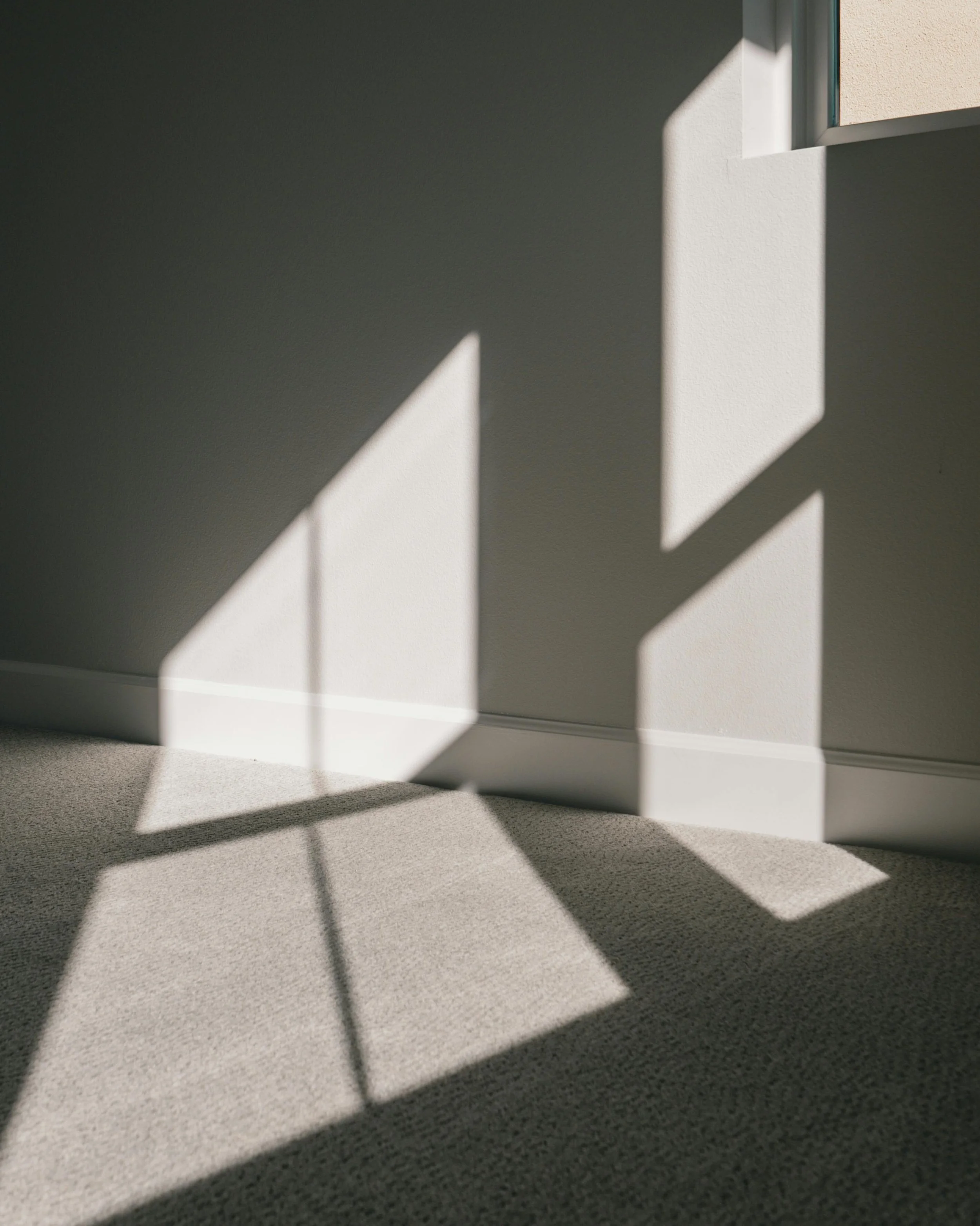 Clean bedroom with sun shining through on carpet and walls