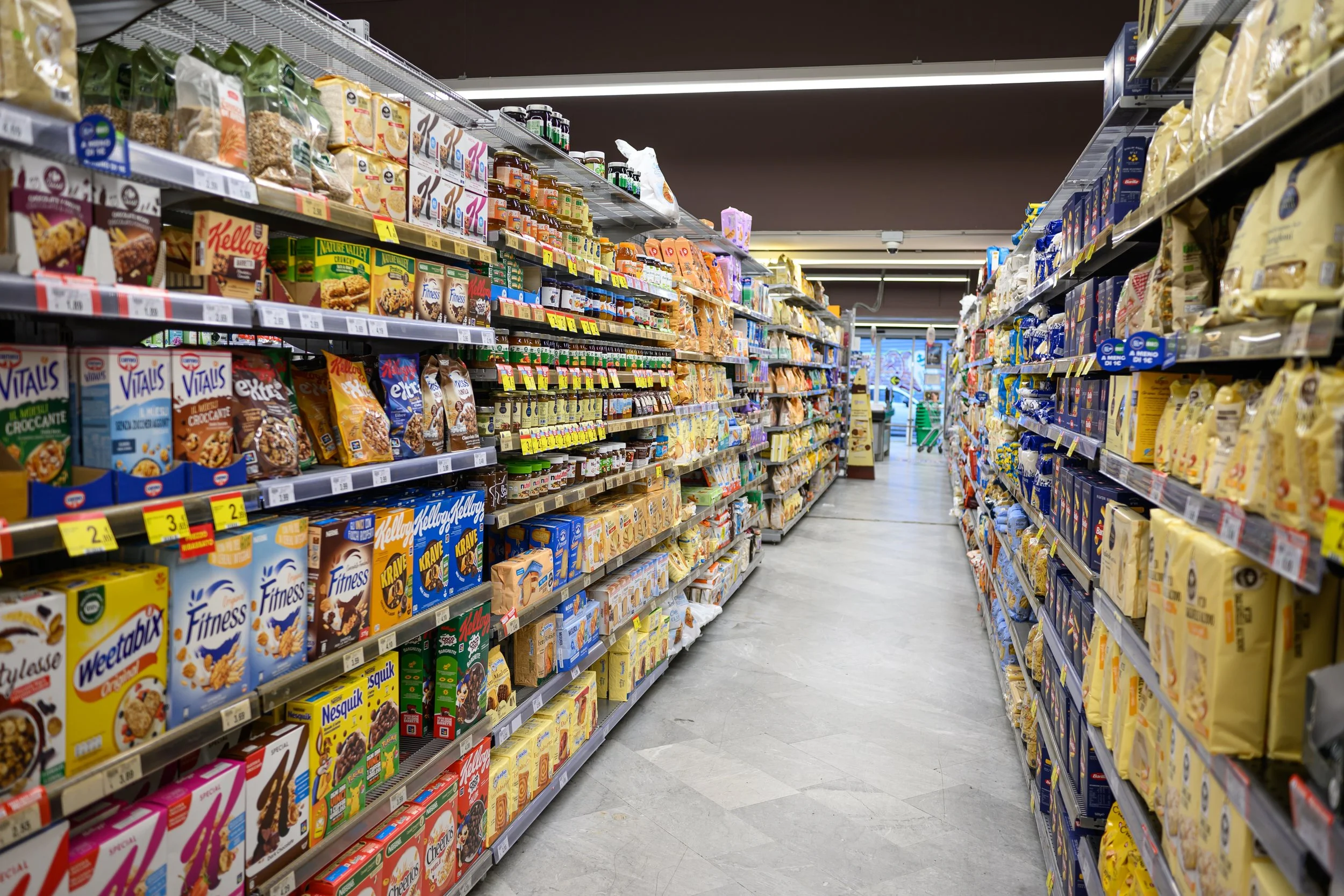 Aisle in a grocery store filled with breakfast cereals and snack foods on shelves.