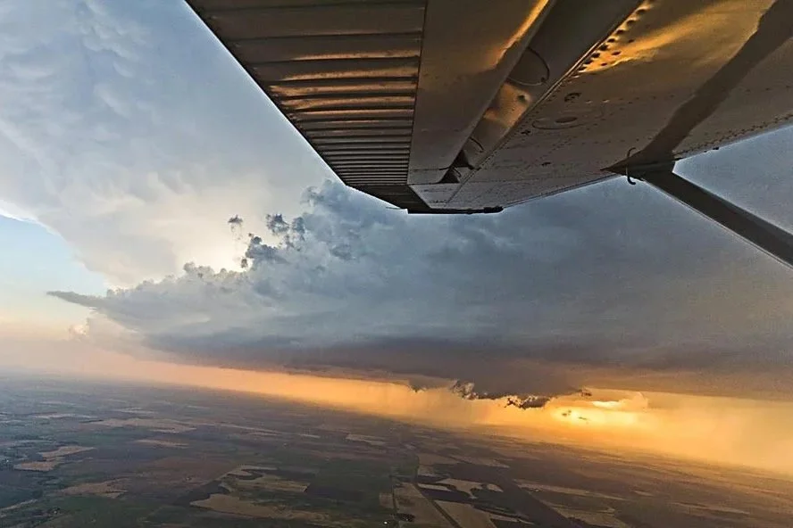 Storm Chaser Caleb Elliott flying next to a tornado warned supercell thunderstorm with a wall cloud underneath