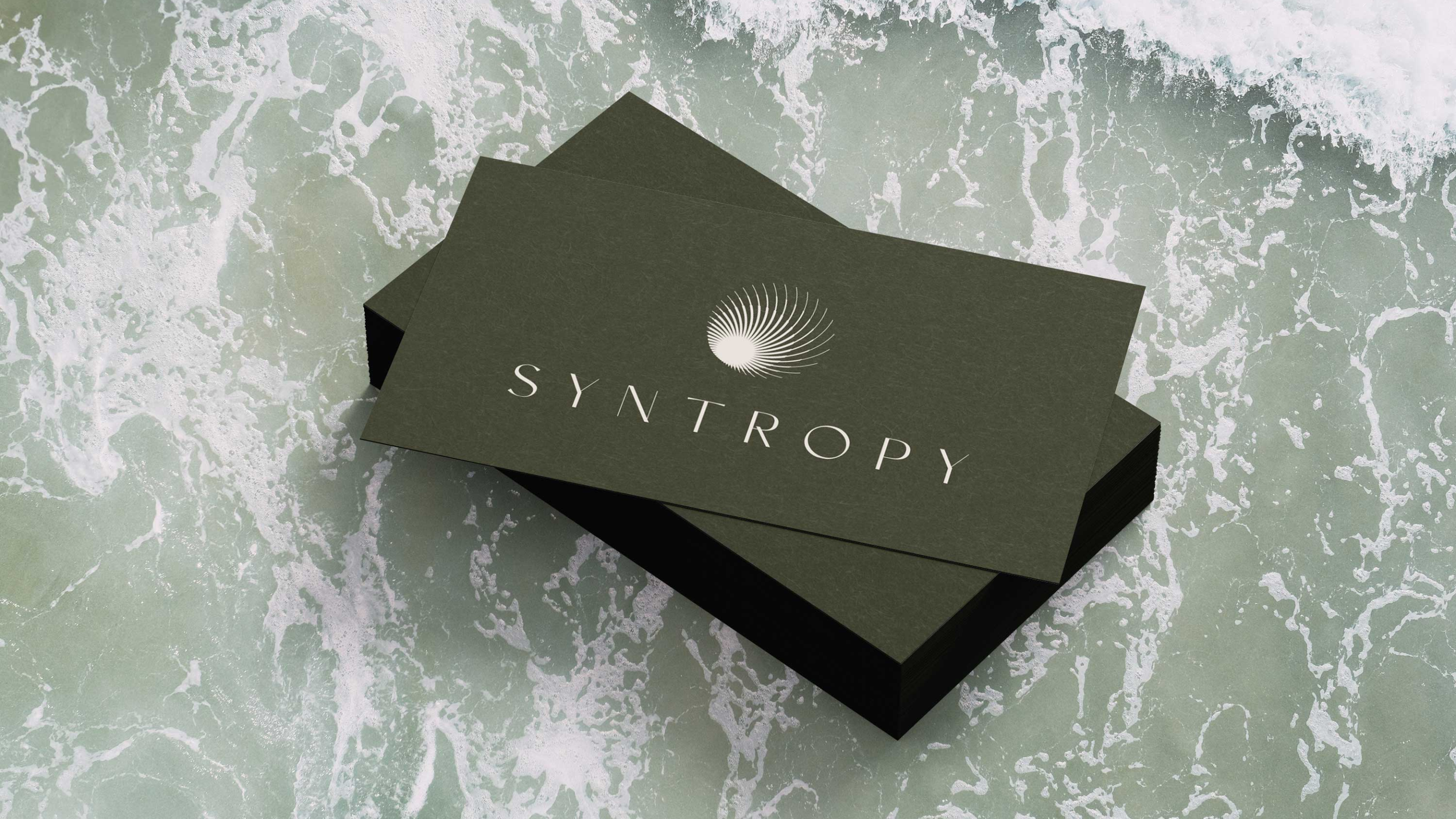 Stack of business cards or flyers with the word 'SYNTROPY' and a spiral logo on a textured surface.