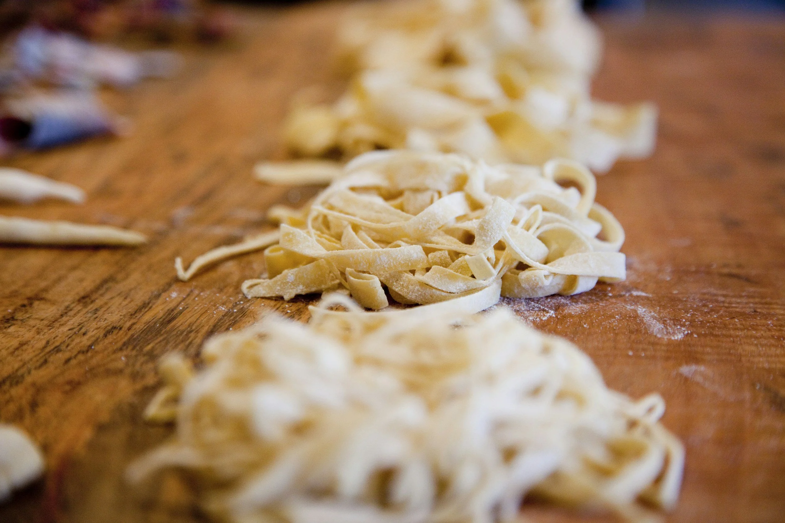 Pastas fraîches coupées en forme de fettuccine sur une surface en bois
