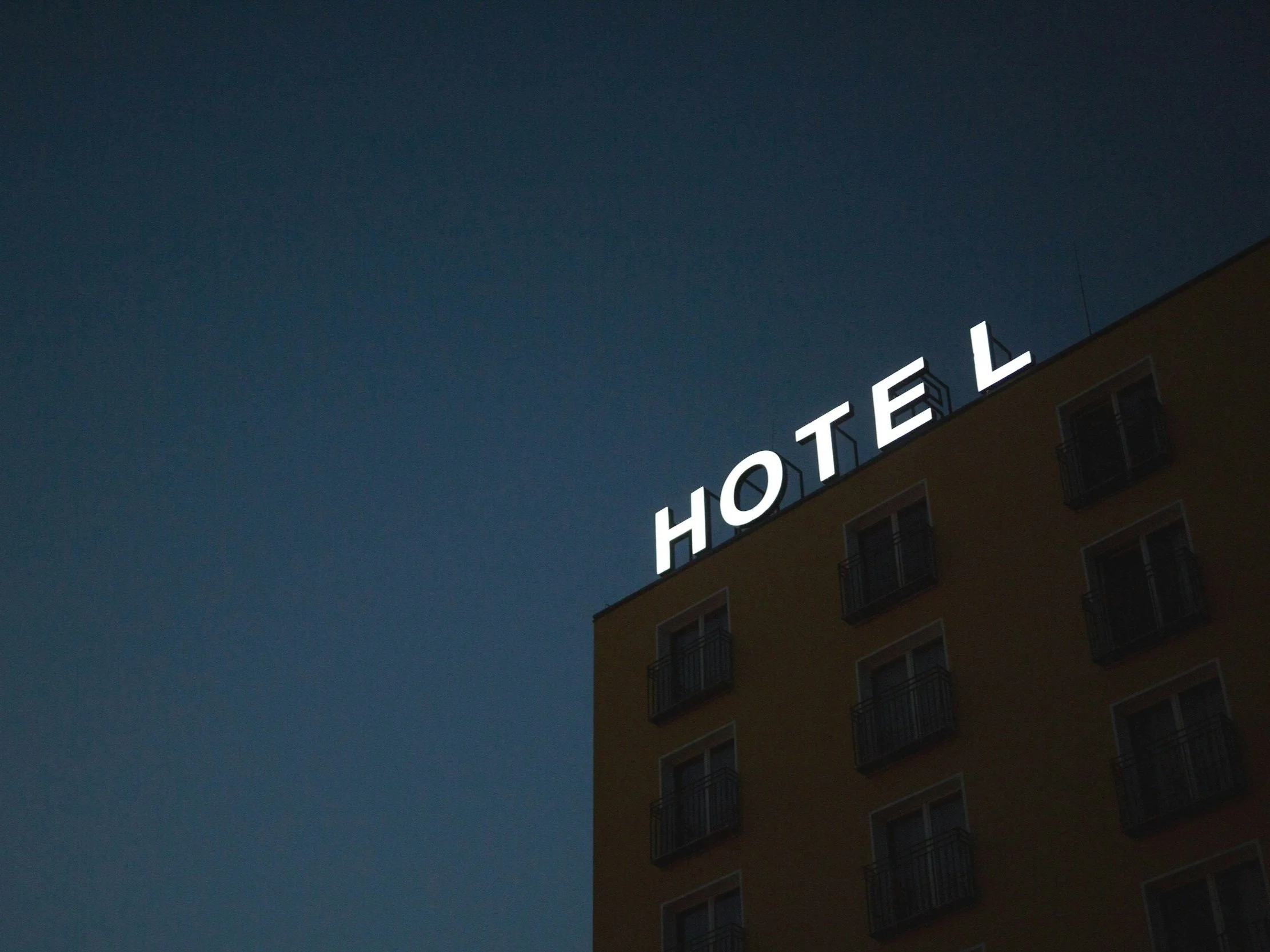 Un bâtiment d'hôtel avec une enseigne lumineuse indiquant 'HOTEL' sur le toit, photographié la nuit.