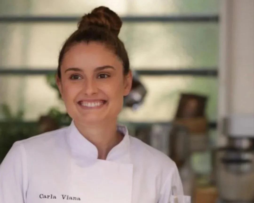 Carla Viana souriante en uniforme de chef dans une cuisine