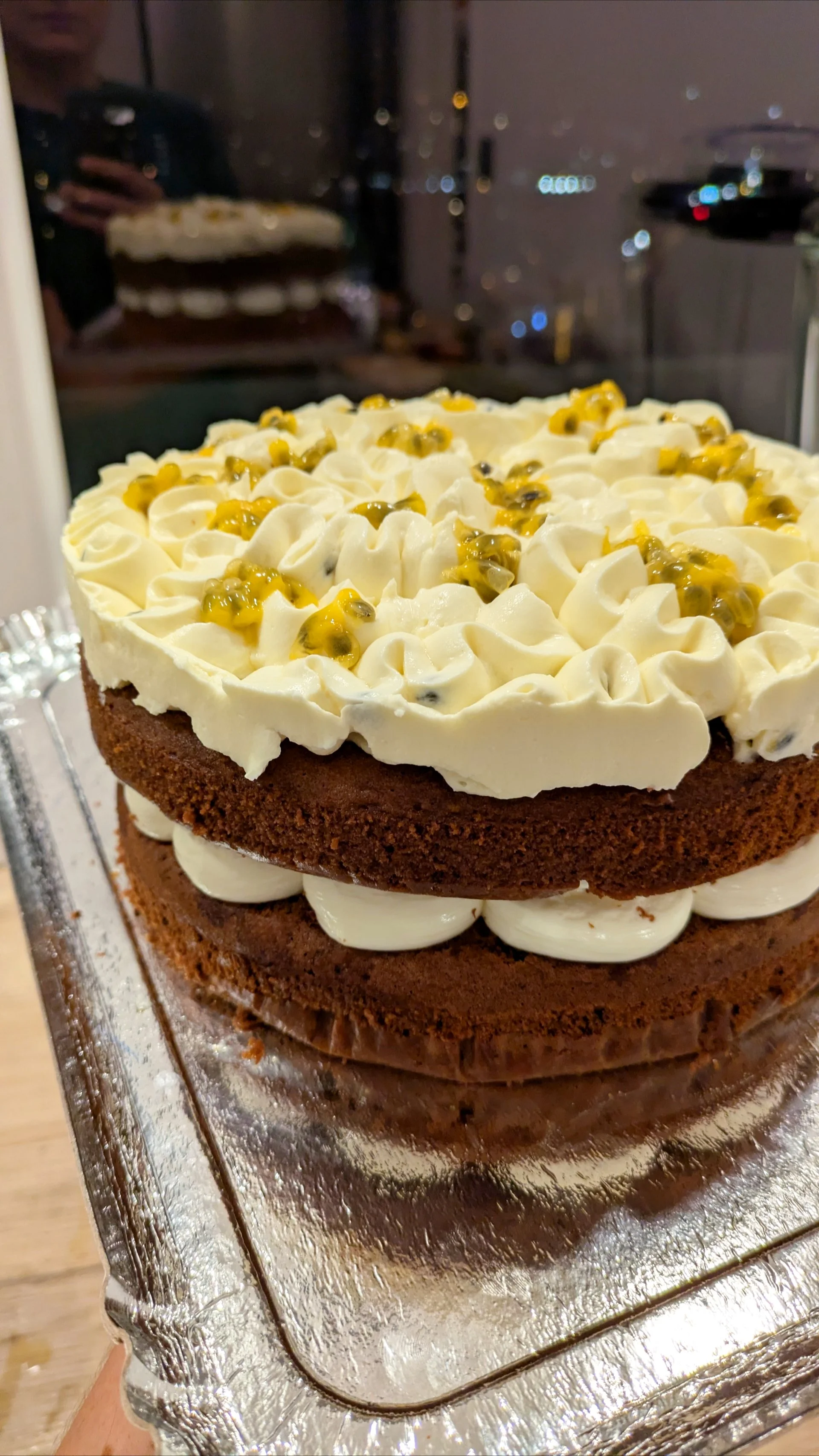 Gâteau au chocolat avec des couches de crème et de passion, décoré de crème fouettée et de fruits de passion sur le dessus.