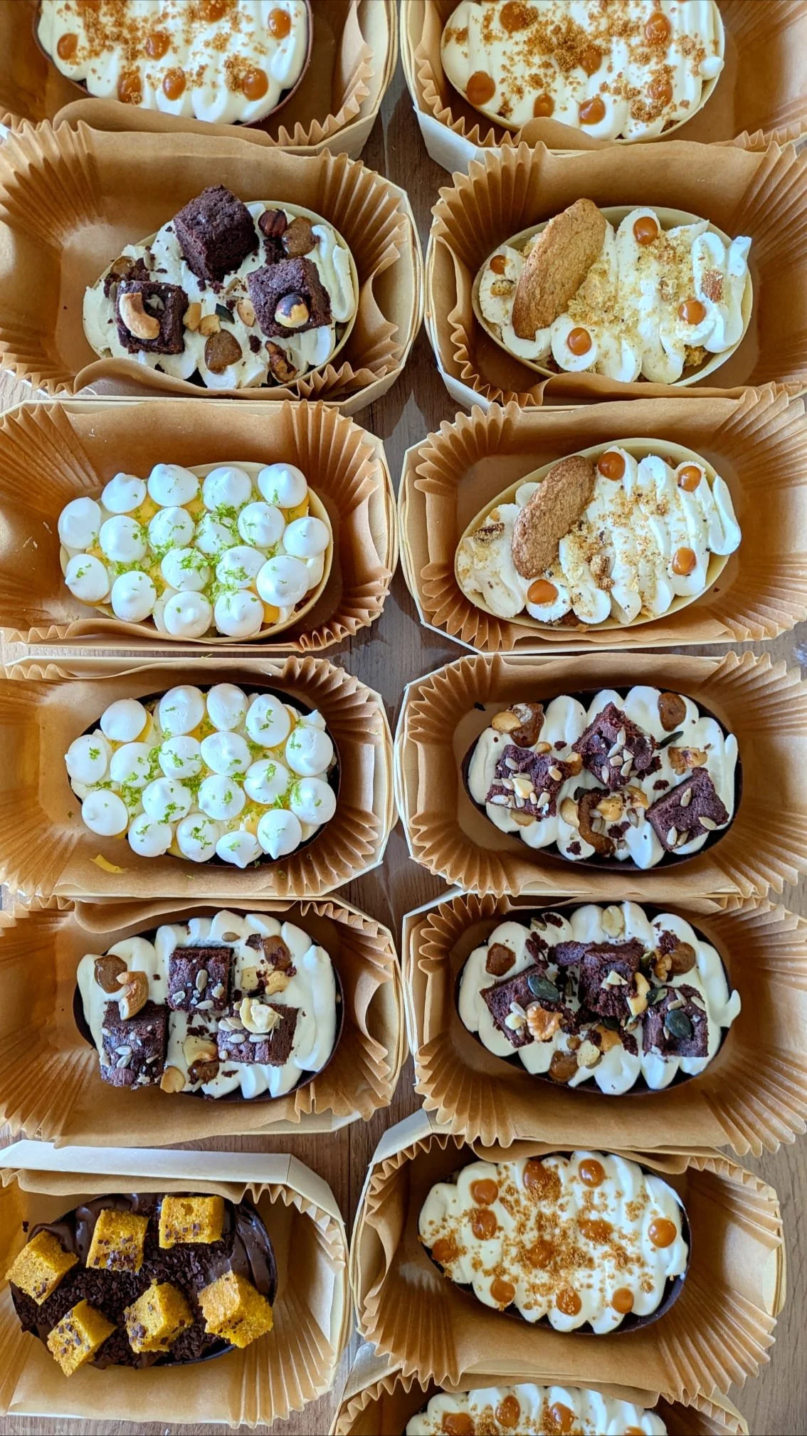 Une sélection de desserts, principalement des œufs en chocolat décorés avec différentes garnitures et toppings, dans des caissettes en papier.