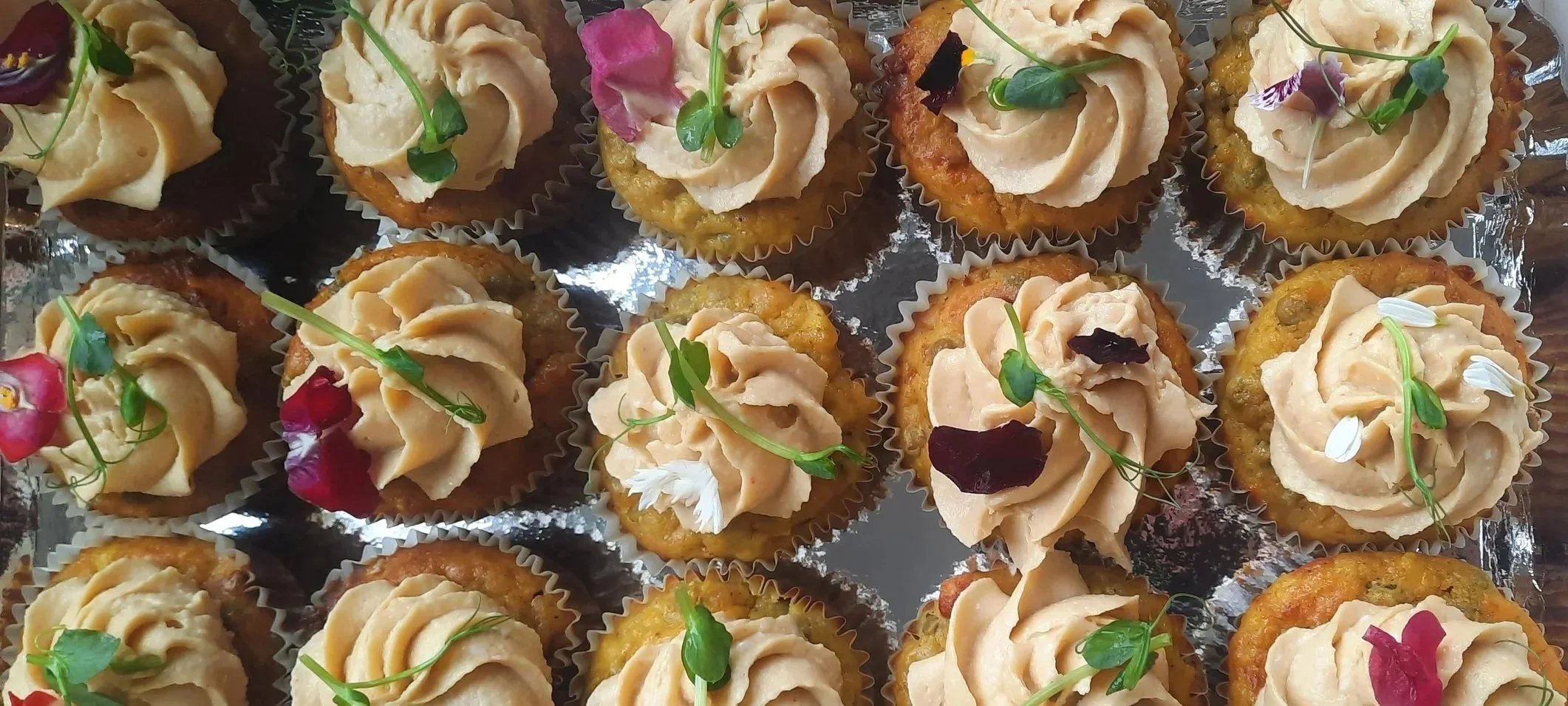 Petites pâtisseries avec crème décorée de fleurs et de feuilles vertes.