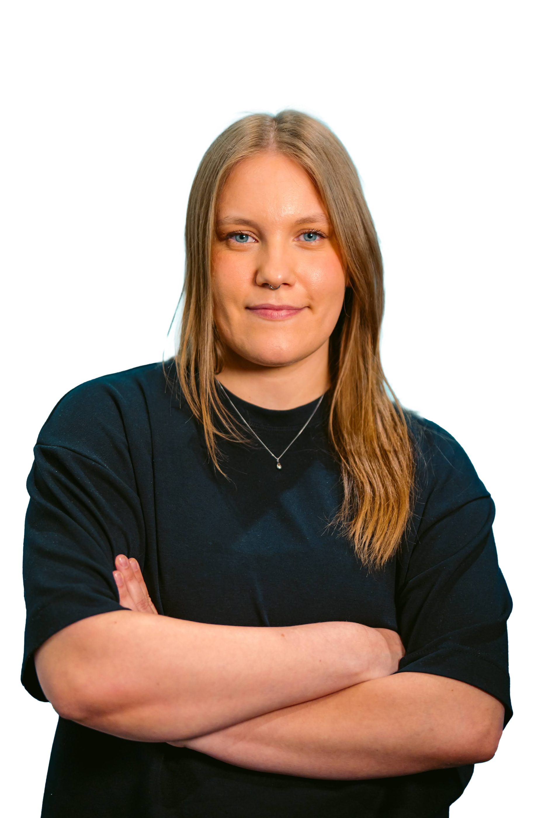 A woman with long blonde hair and blue eyes, wearing a black shirt and a silver necklace, standing with her arms crossed and smiling subtly against a solid black background.