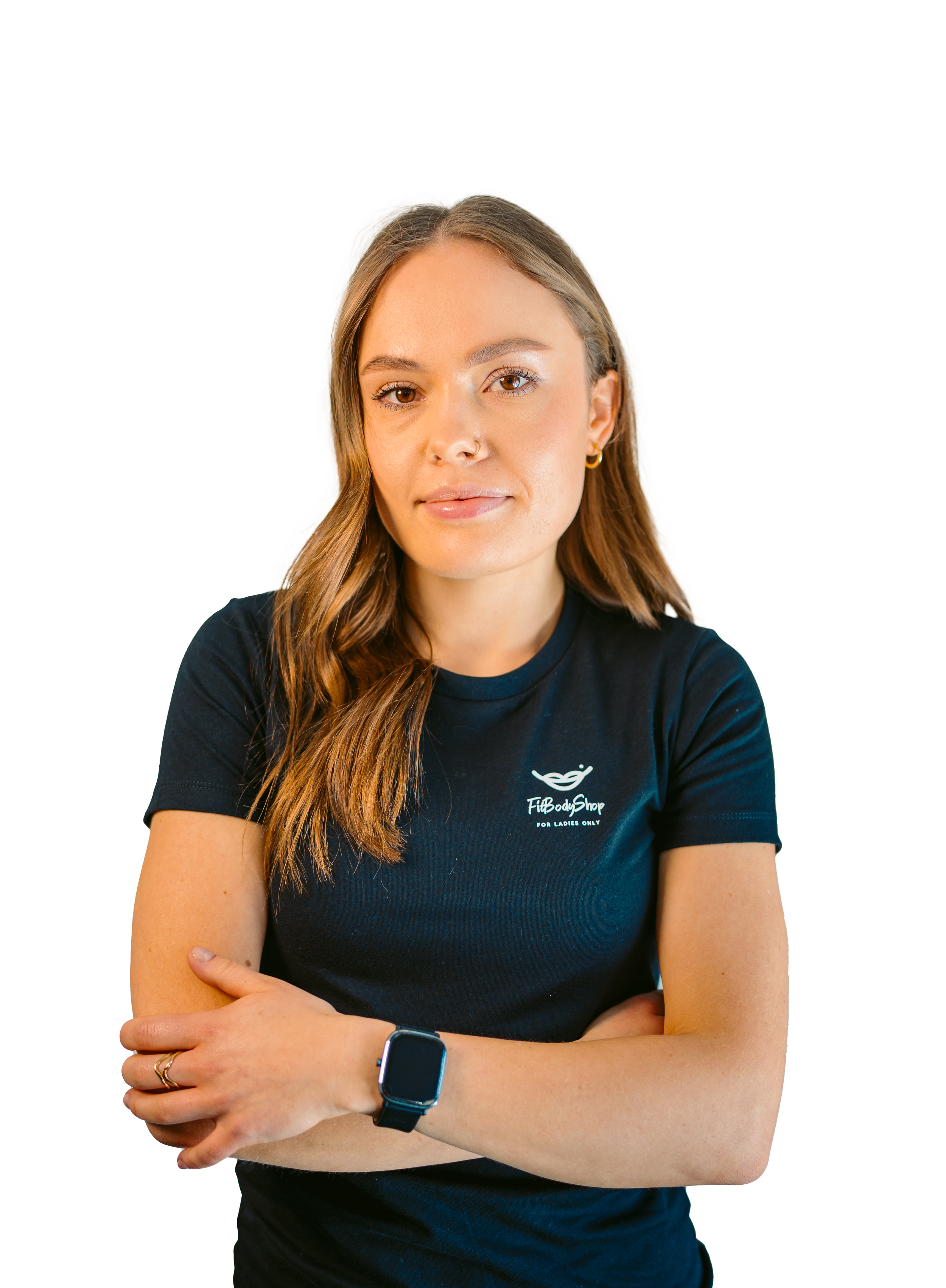 A young woman with long brown hair, wearing a navy blue T-shirt with a logo that says 'Fit Body Shop for Ladies Only,' and a smartwatch on her left wrist, standing with arms crossed.