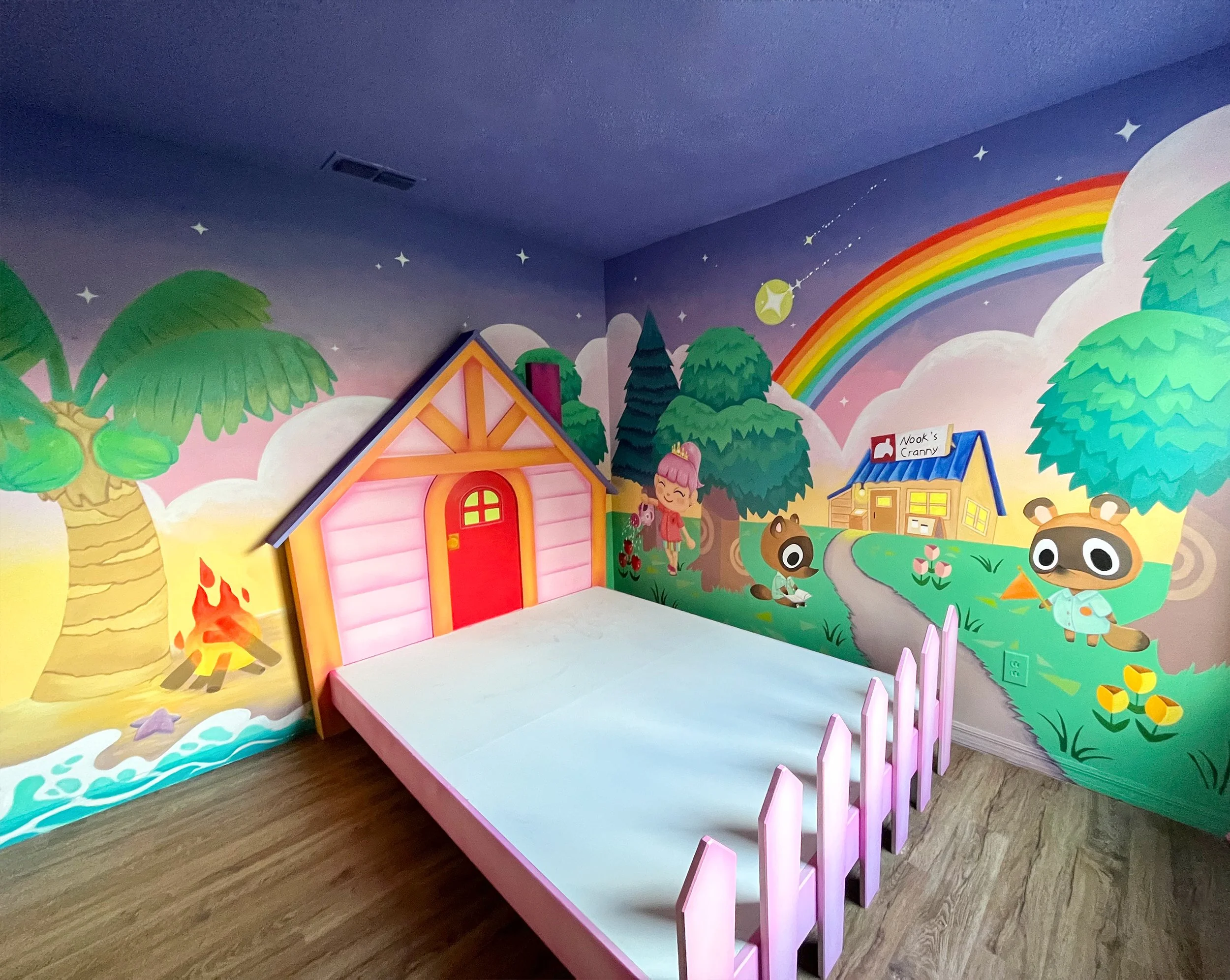 Colorful children's playroom with a mural of trees, animals, a rainbow, and a small house labeled "Wook's Cranny." There is a pink bed with a fence around it.