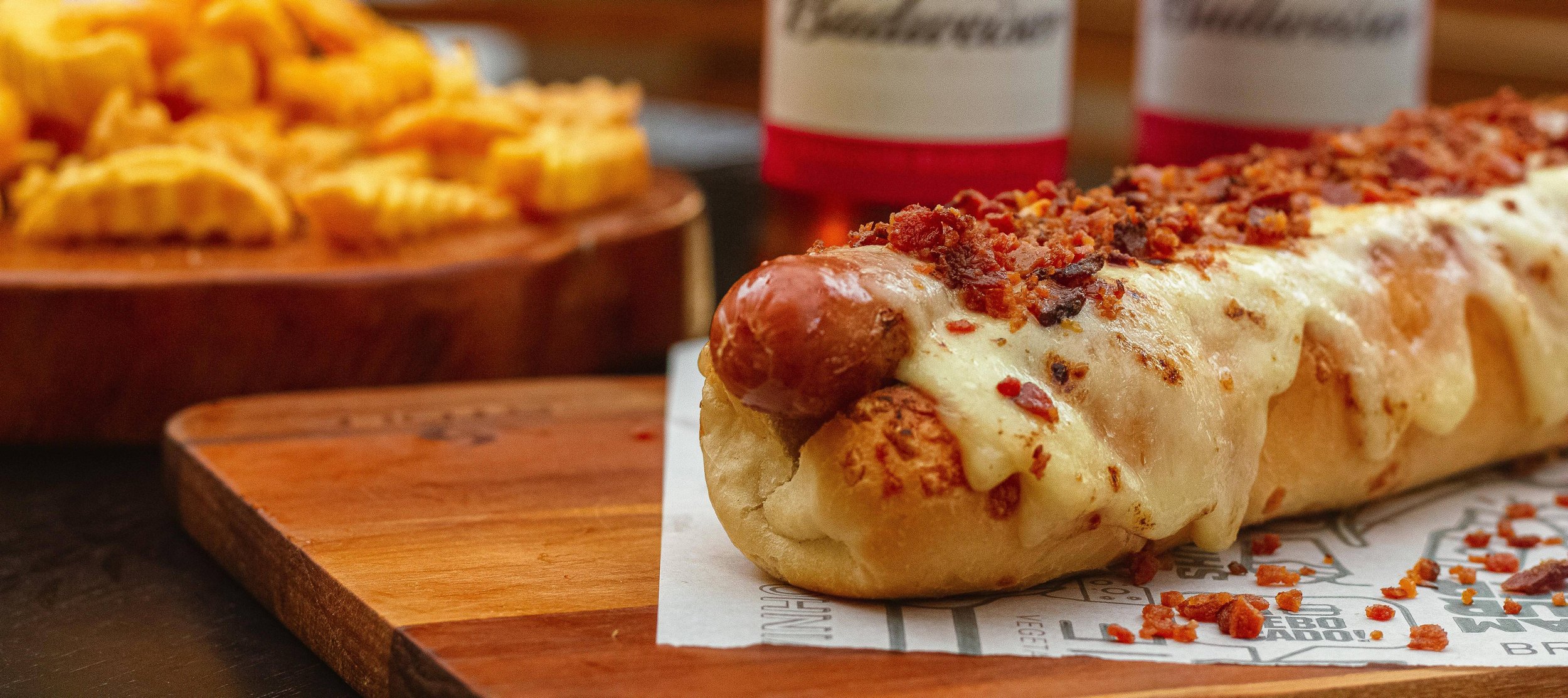 a hotdog covered in melted cheese and topped with bacon bits