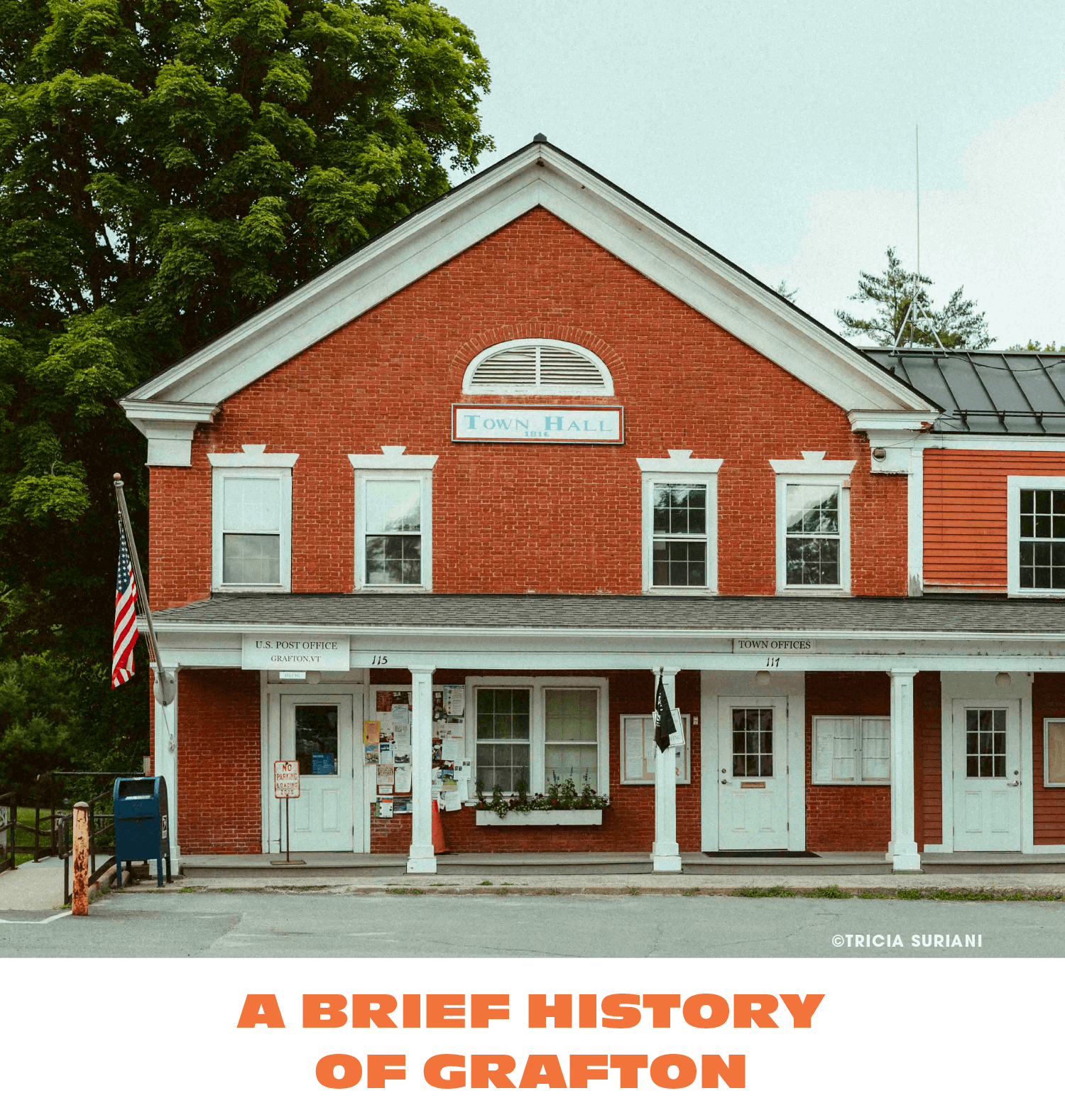 The image shows a historic red brick building with a sign that reads 'Town Hall' on the front, located in Grafton, Vermont. The upper part of the building has three windows and an arched vent. The lower level has a porch with notices and flyers, a wi