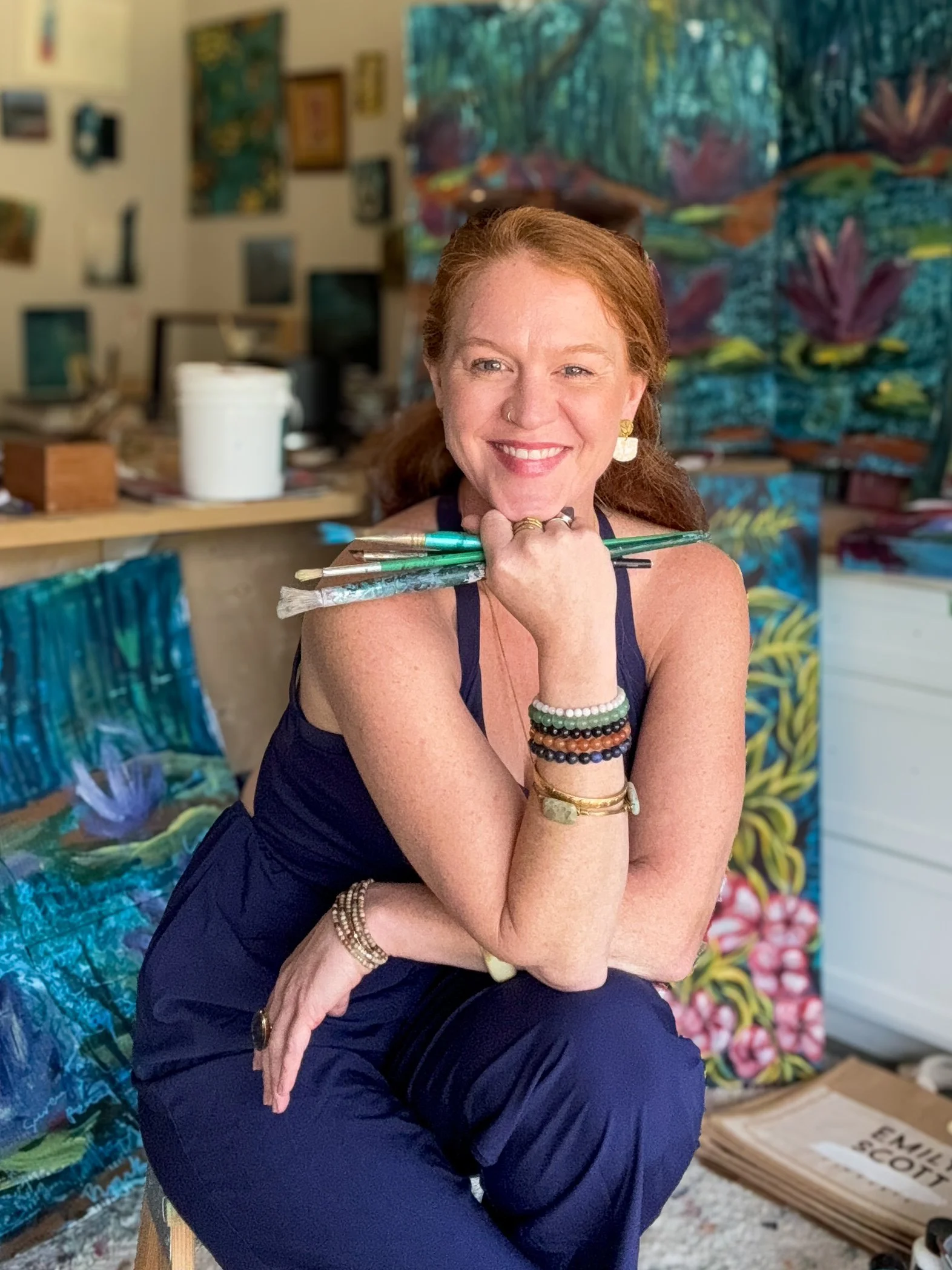Emily Scott, encaustic painting artist, surrounded by her original artwork in her studio