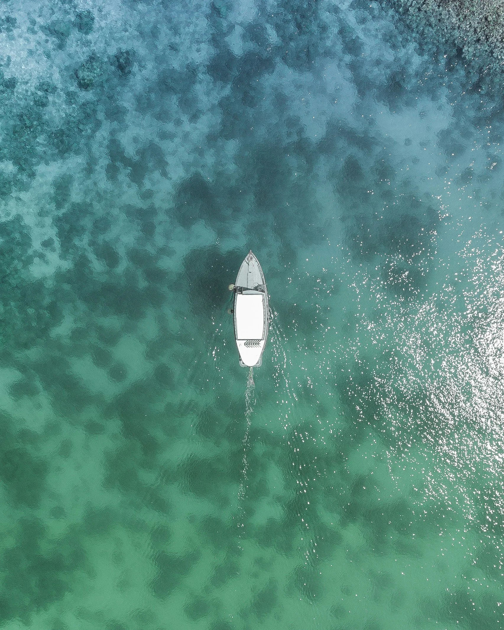 Aerial view of a boat in clear turquoise water.